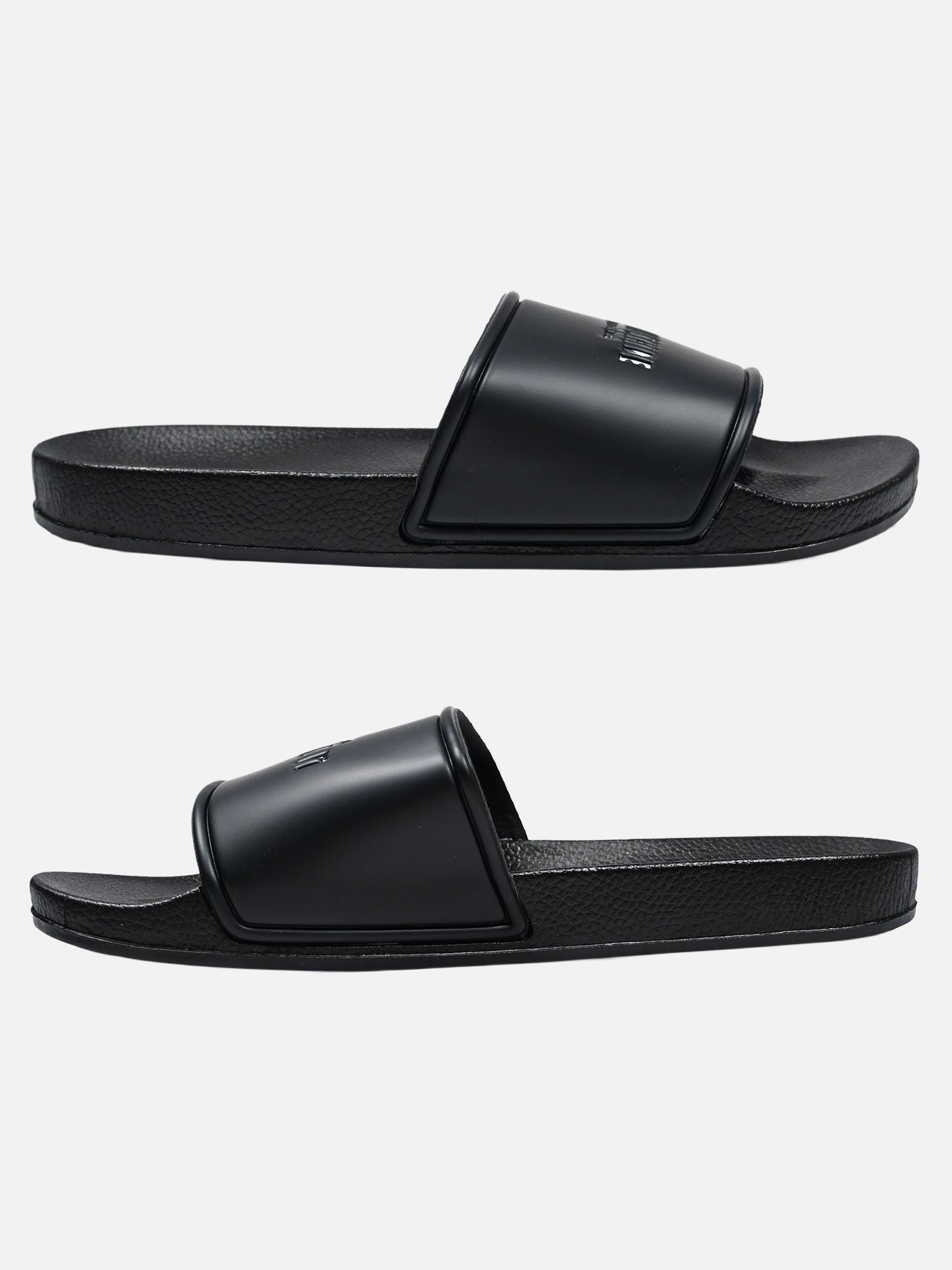 Two black La Machine Logo Slides/Slippers by La Machine Cycle Club, featuring textured soles and wide straps, displayed side by side on a plain white background—ideal for cyclists seeking comfort after a ride.