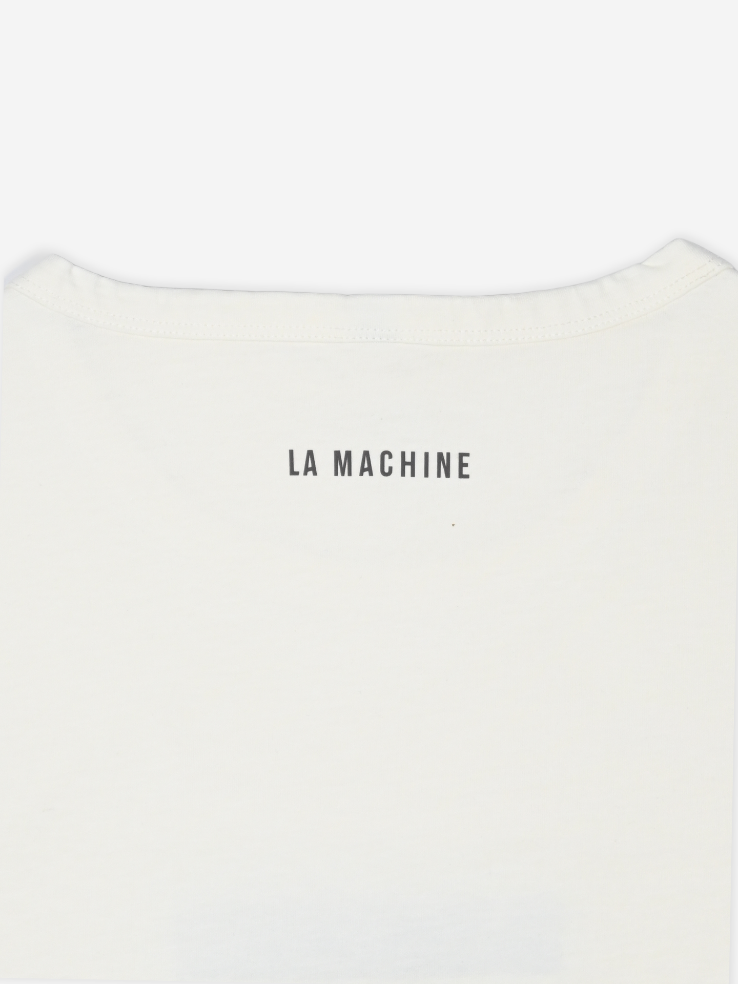 Close-up of the upper back of the Bib Number 13 - T-shirt in off-white by La Machine Cycle Club, featuring LA MACHINE printed in bold black capitals below the neckline.
