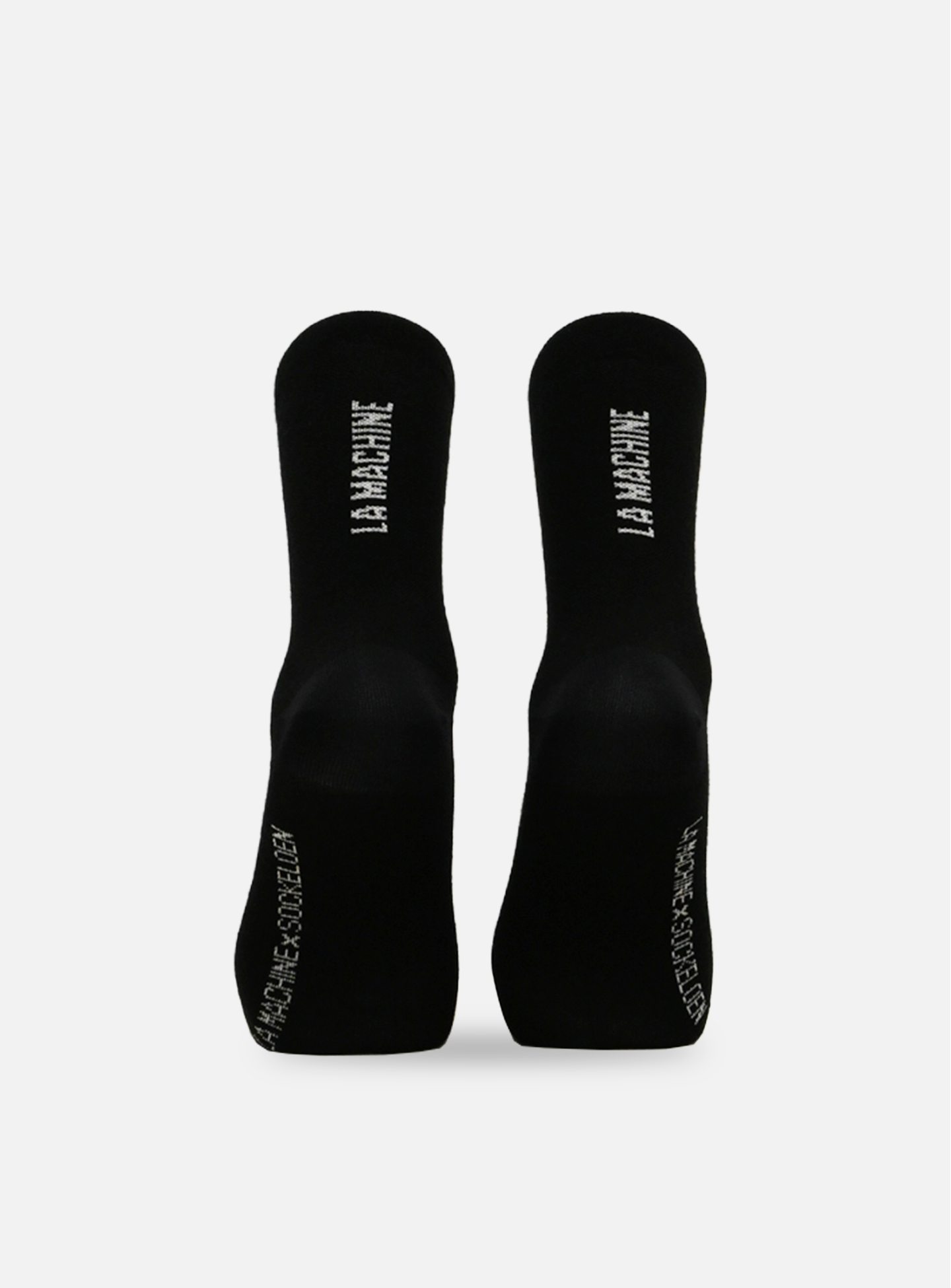 The La Machine Cycle Clubs black unisex Merino cycling socks feature LA MACHINE on the soles and NO FAME. NO GLORY. JUST CYCLING. near the toes—a perfect 4-season choice for any ride.