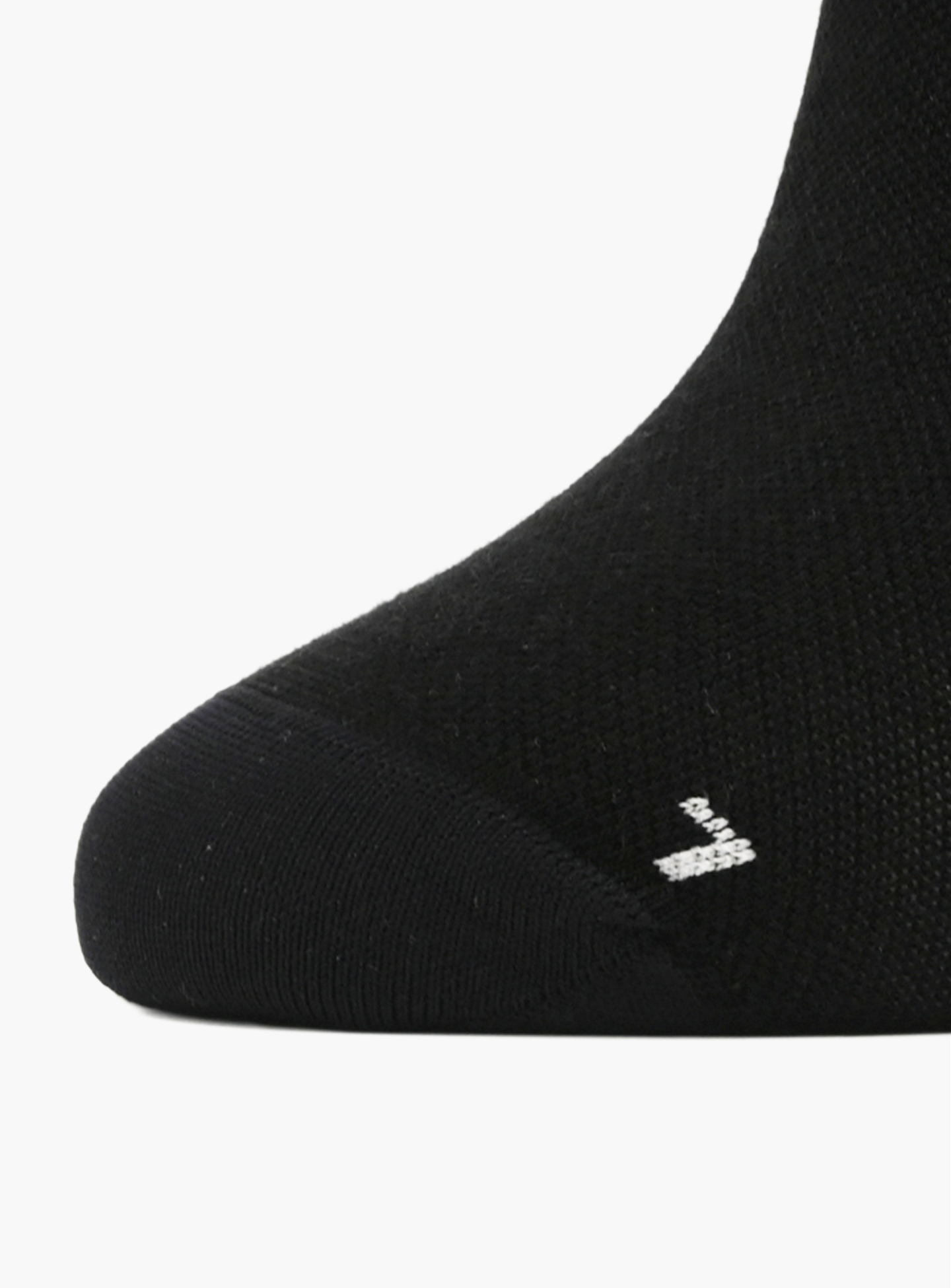 A close-up of the La Machine Logo Cycling Socks in black merino by La Machine Cycle Club, featuring a small white zigzag logo near the toe on a unisex design.