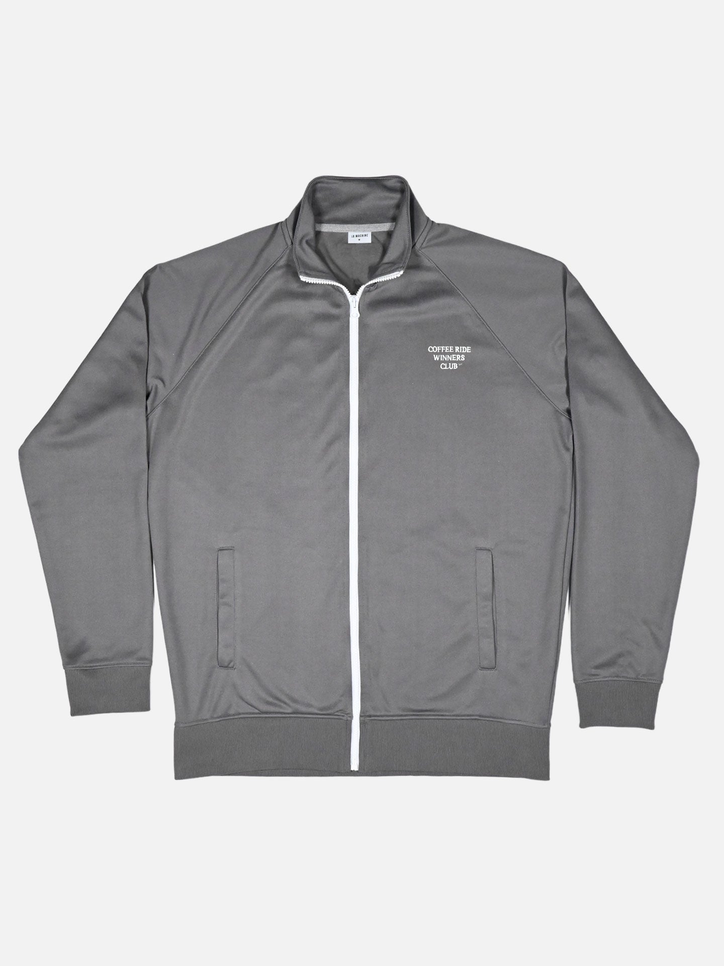 The La Machine Cycle Club Coffee Ride Winners Club Track Jacket in Steel Grey features white trim, two front pockets, and COFFEE RUN CLUB printed on the left chest—perfect for your next coffee ride or as a stylish cycling track jacket.