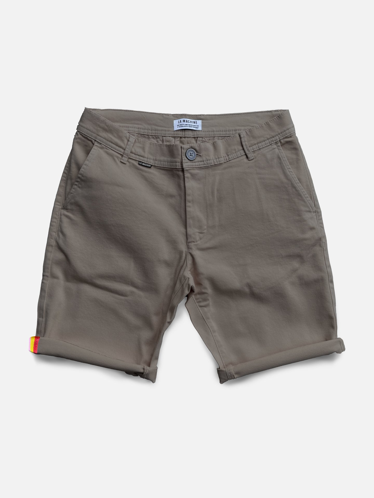 The Grand Tours - Rest Day Bermuda shorts by La Machine Cycle Club come in grey with cuffed hems, front pockets, belt loops, and a button closure. They offer a semi-tailored fit and feature a subtle red and yellow detail on the left leg cuff.