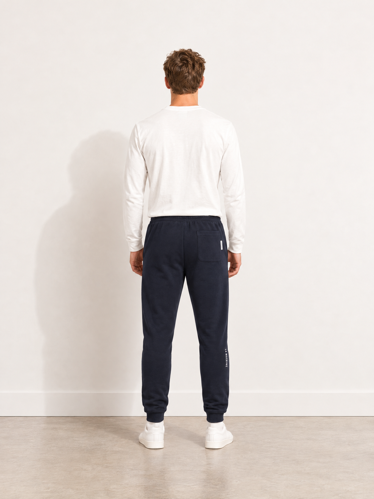 A model wearing the Tarmac Cartel sweatpants in dark navy blue.