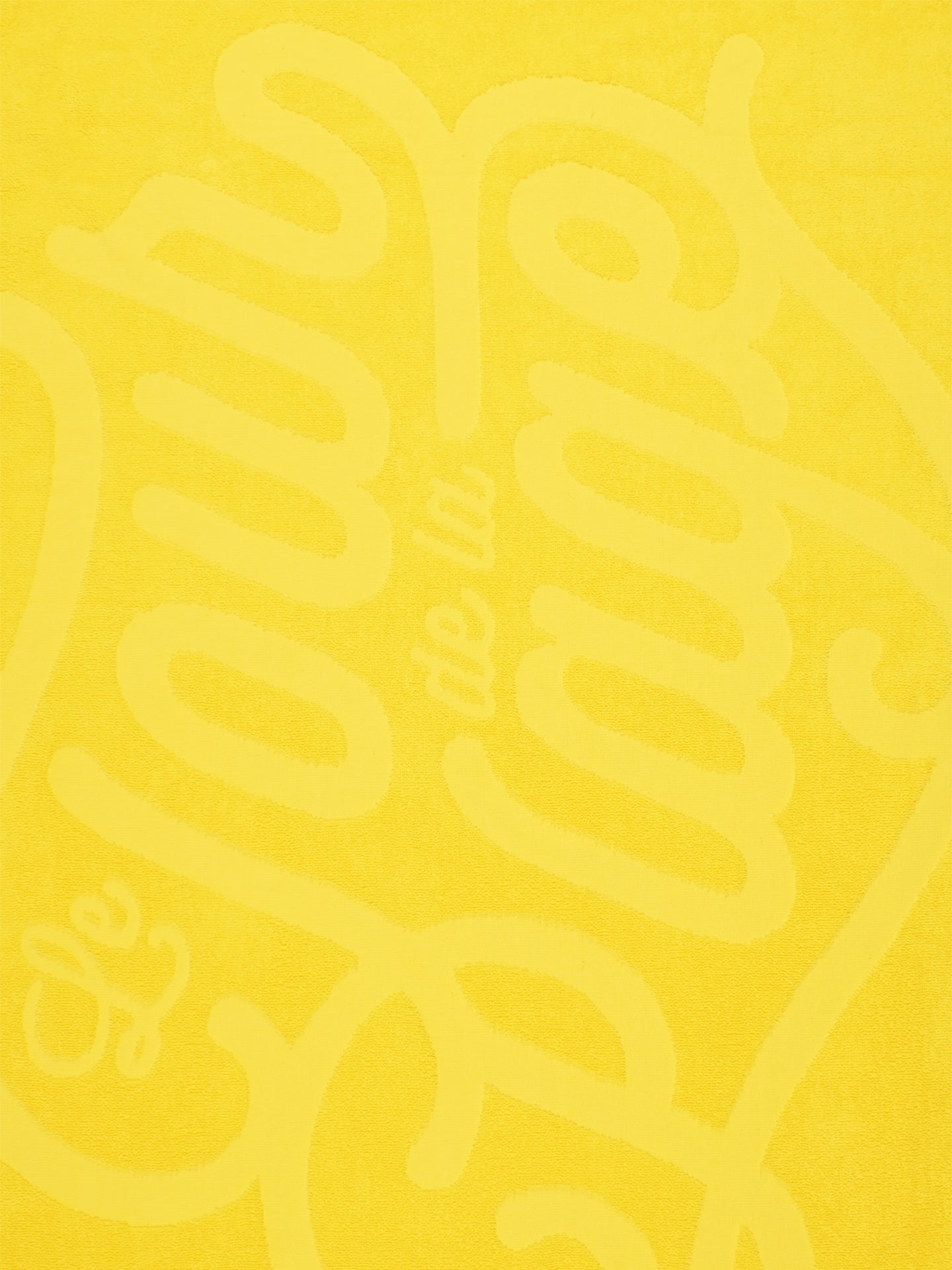 The Le Tour de la Plage Beach Towel from La Machine Cycle Club features bold, cursive lettering inspired by the iconic yellow jersey.