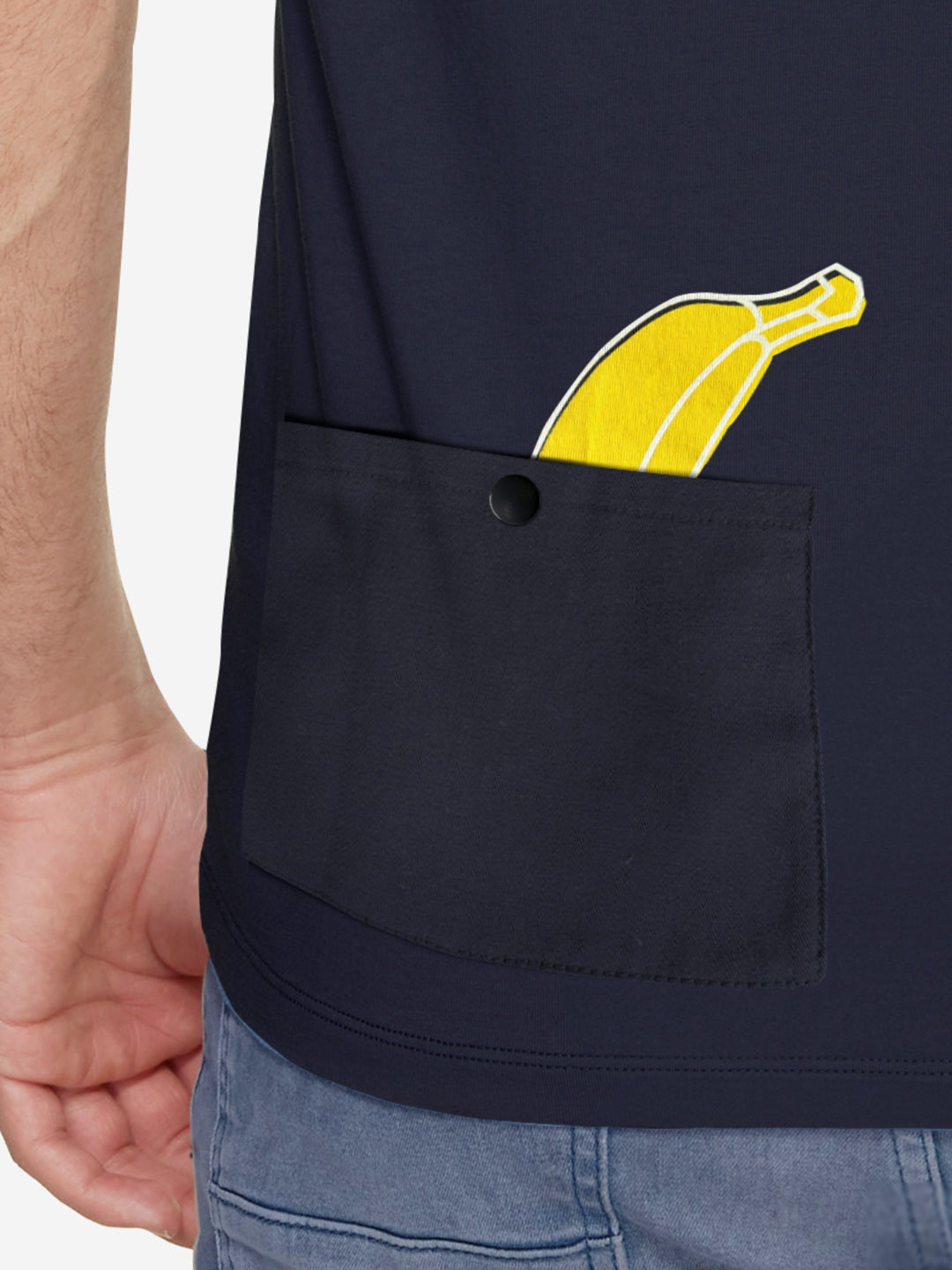 A person wears the In the Pocket mens T-shirt by La Machine Cycle Club in navy, featuring a front pocket with a playful yellow cartoon banana graphic peeking out, paired with blue jeans.