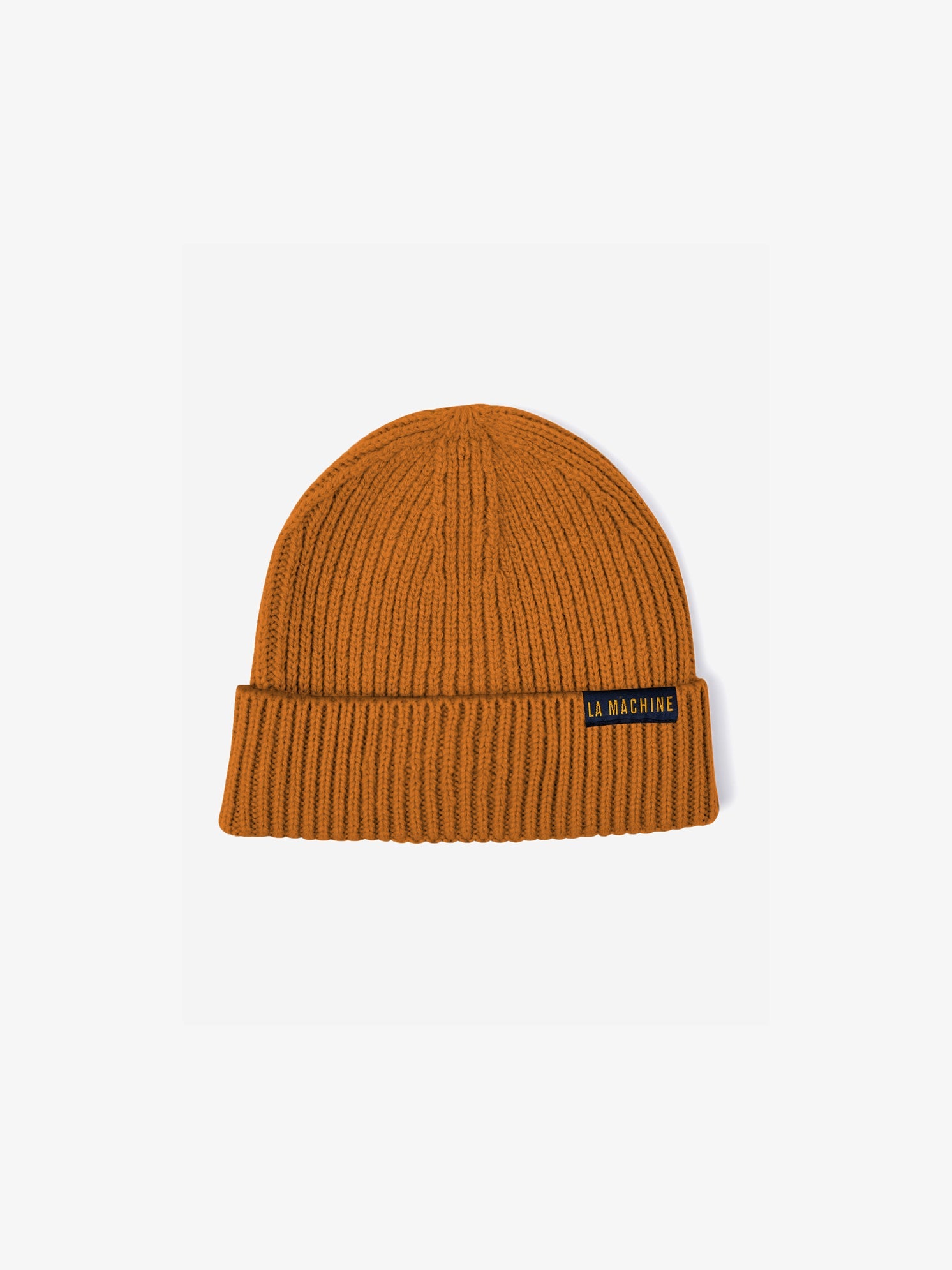 The La Machine - Beanie - Burnt Orange by La Machine Cycle Club features ribbed fabric, a folded brim, and a black LA MACHINE patch label—an essential unisex accessory for winter style.