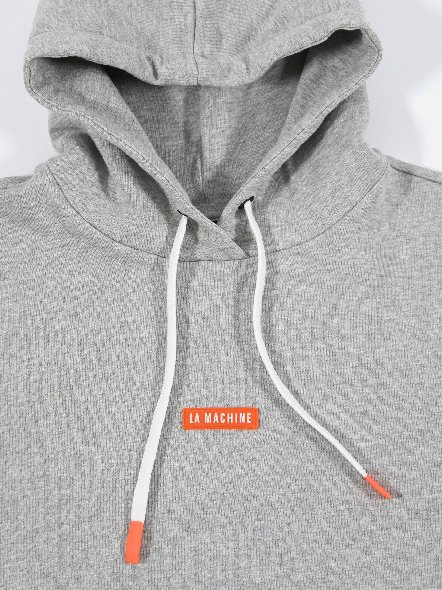 The Beyond the bike - Hoodie - Melange Grey by La Machine Cycle Club features white drawstrings tipped in orange, a small orange LA MACHINE chest patch, a hidden pocket, and unisex design—perfect for everyday style and convenience.