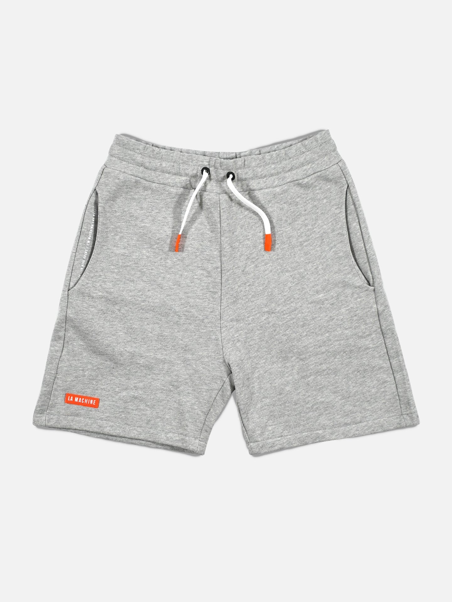 The Beyond the Bike Sweatshorts in Melange Grey by La Machine Cycle Club feature a relaxed fit, elastic waistband, white drawstrings with orange tips, side pockets, and a red patch with white text on the lower left leg.
