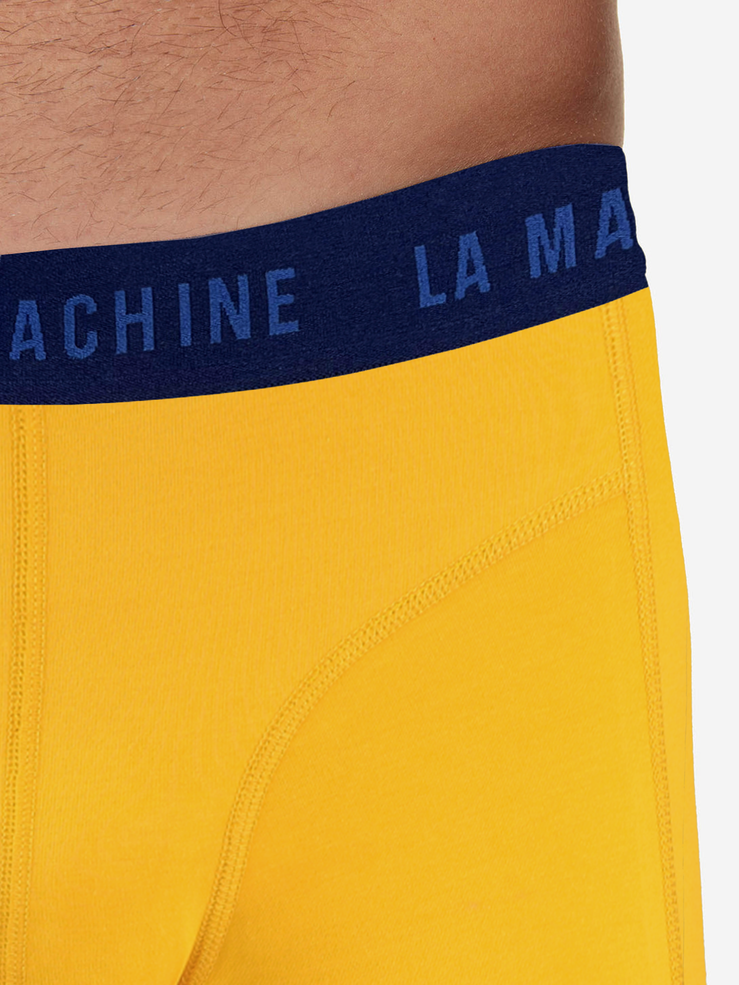 Close-up of a person wearing La Machine Cycle Club’s Tour Yellow Boxershorts, bright yellow with a navy blue LA MACHINE waistband—ideal for cyclists. Only the lower abdomen and upper thigh are shown.