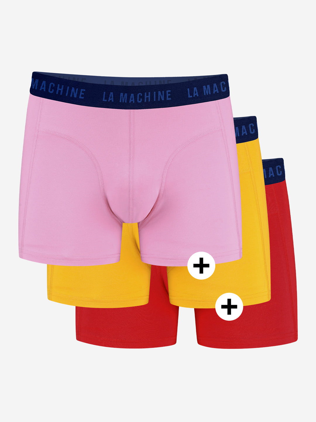 Three pairs of La Machine Cycle Club Grand Tours boxershorts, in pink, yellow, and red with navy LA MACHINE waistbands, are stacked in an overlapping arrangement on a plain white background.