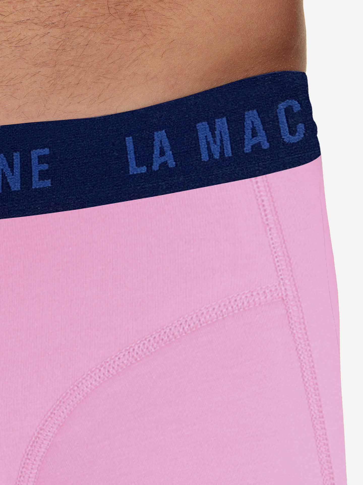 Close-up of a person wearing La Machine - Boxershorts - Giro Pink by La Machine Cycle Club, featuring pink fabric, a dark blue waistband with partial LA MA text, visible stitching, and a contoured pouch inspired by Giro dItalia style.