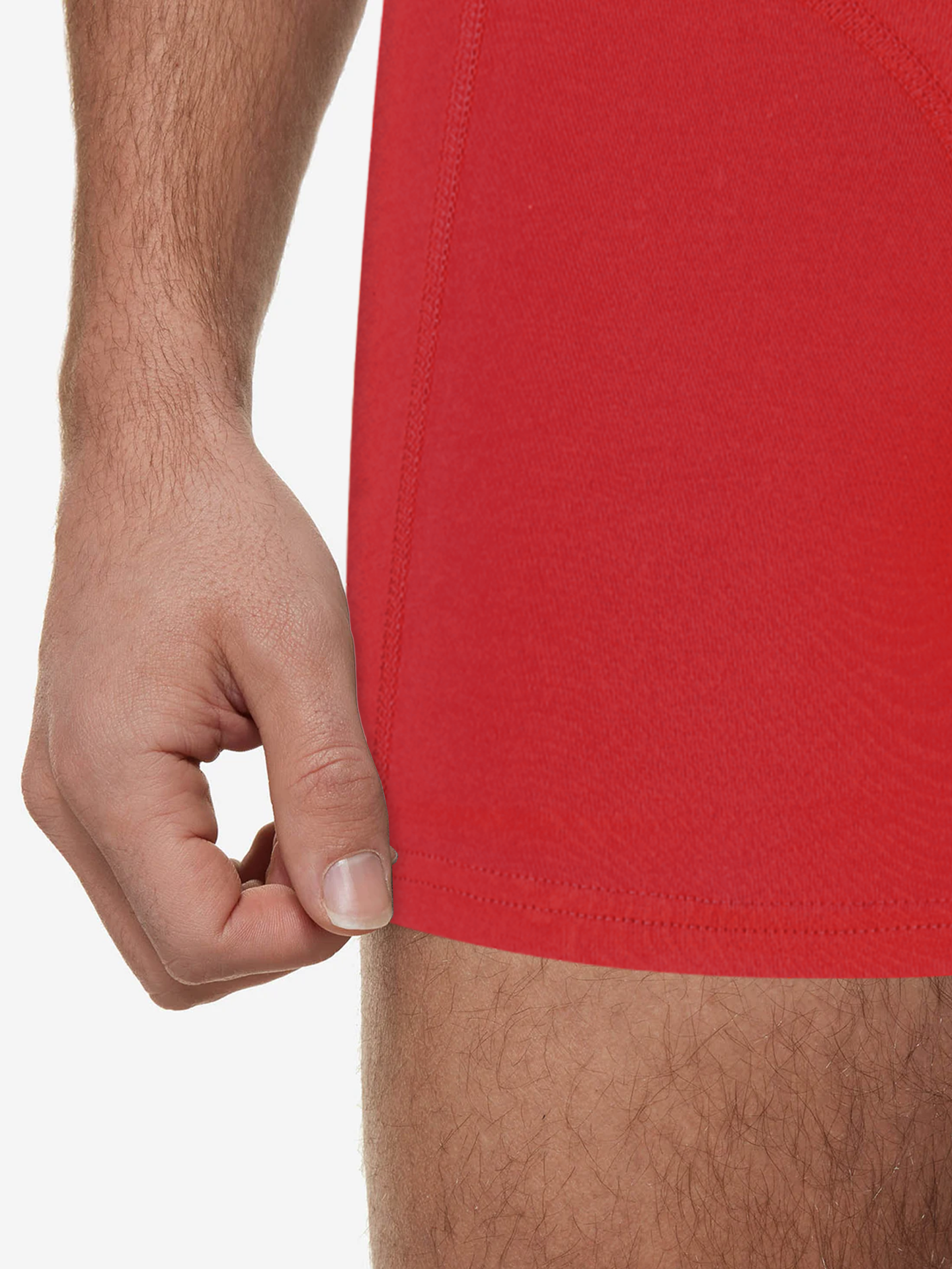 A close-up shows a hand gently pulling the hem of La Machine - Boxershorts - Vuelta Red by La Machine Cycle Club, revealing part of the upper thigh and arm against a plain white background.