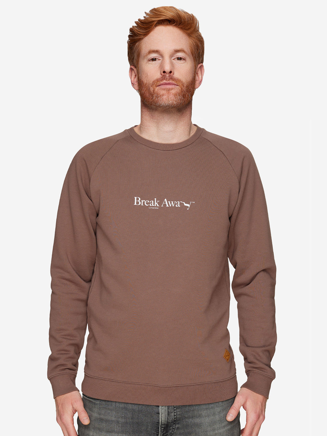 A red-haired, bearded man wears the La Machine Cycle Club Break Away mens sweatshirt in brown, featuring the design on the front, set against a plain white background.