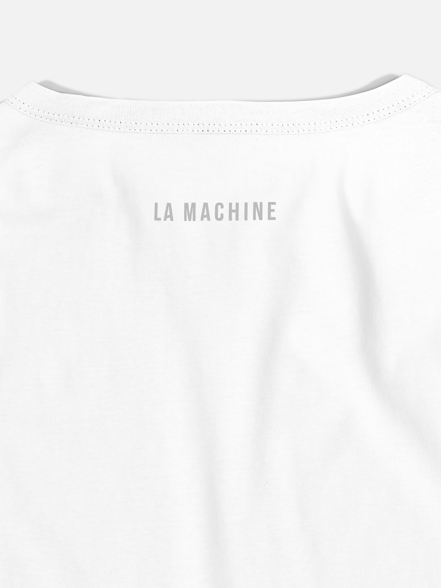A close-up of the back of the Coffee Ride Winners Club - T-shirt - White by La Machine Cycle Club, featuring LA MACHINE in gray uppercase letters near the neckline—ideal for coffee rides or casual cycling.