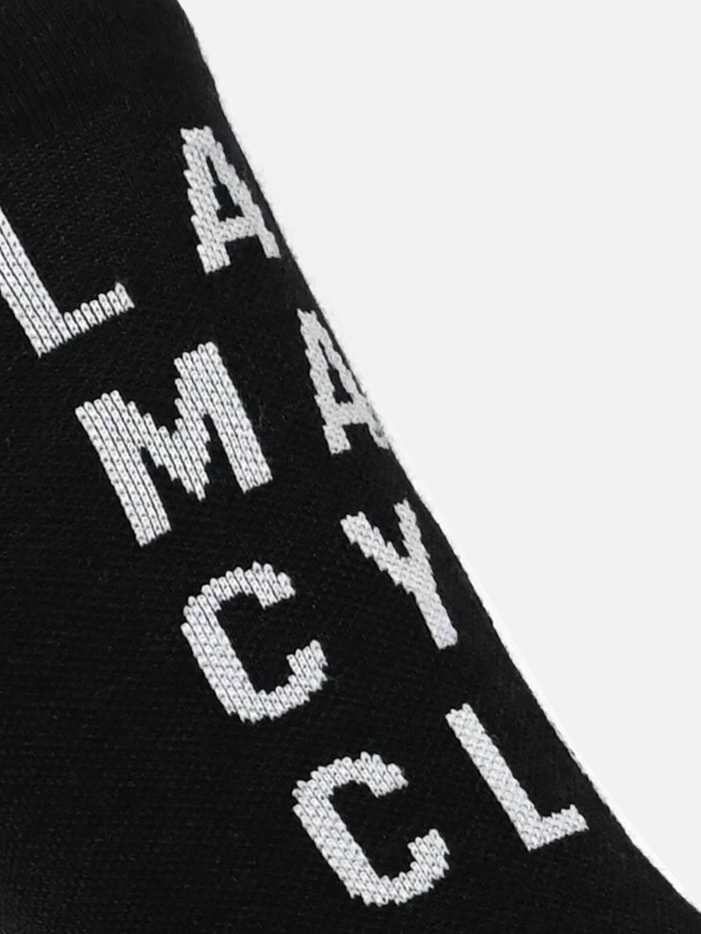 A close-up of black LMCC - Cycling Socks - Merino by La Machine Cycle Club, featuring white vertically-stitched letters—ideal unisex socks for cyclists seeking style and comfort all year round.