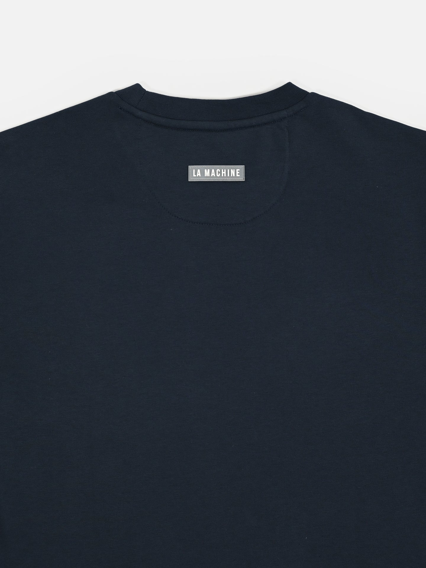 A close-up of the back neckline of the Grand Tours III - Embroidered Sweatshirt by La Machine Cycle Club, featuring a small gray LA MACHINE label.