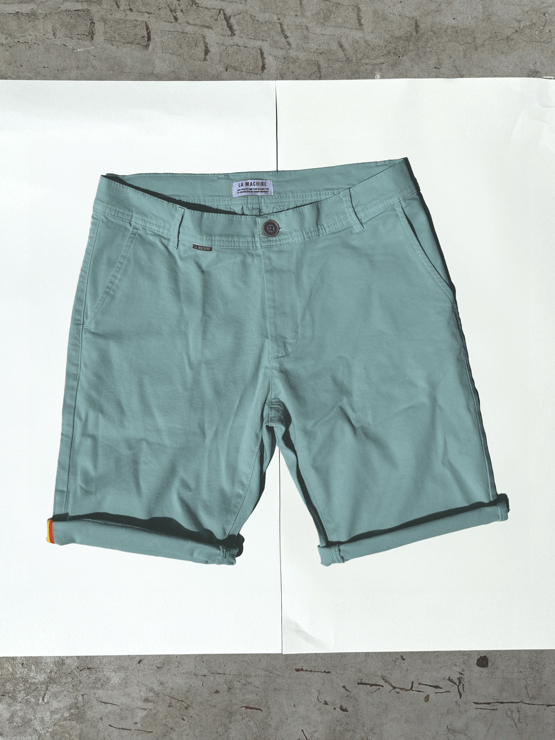 The Grand Tours - Rest Day Bermuda - Antarctics by La Machine Cycle Club: light teal, semi-tailored Bermuda shorts with belt loops and side pockets, shown flat on a white background edged with concrete.