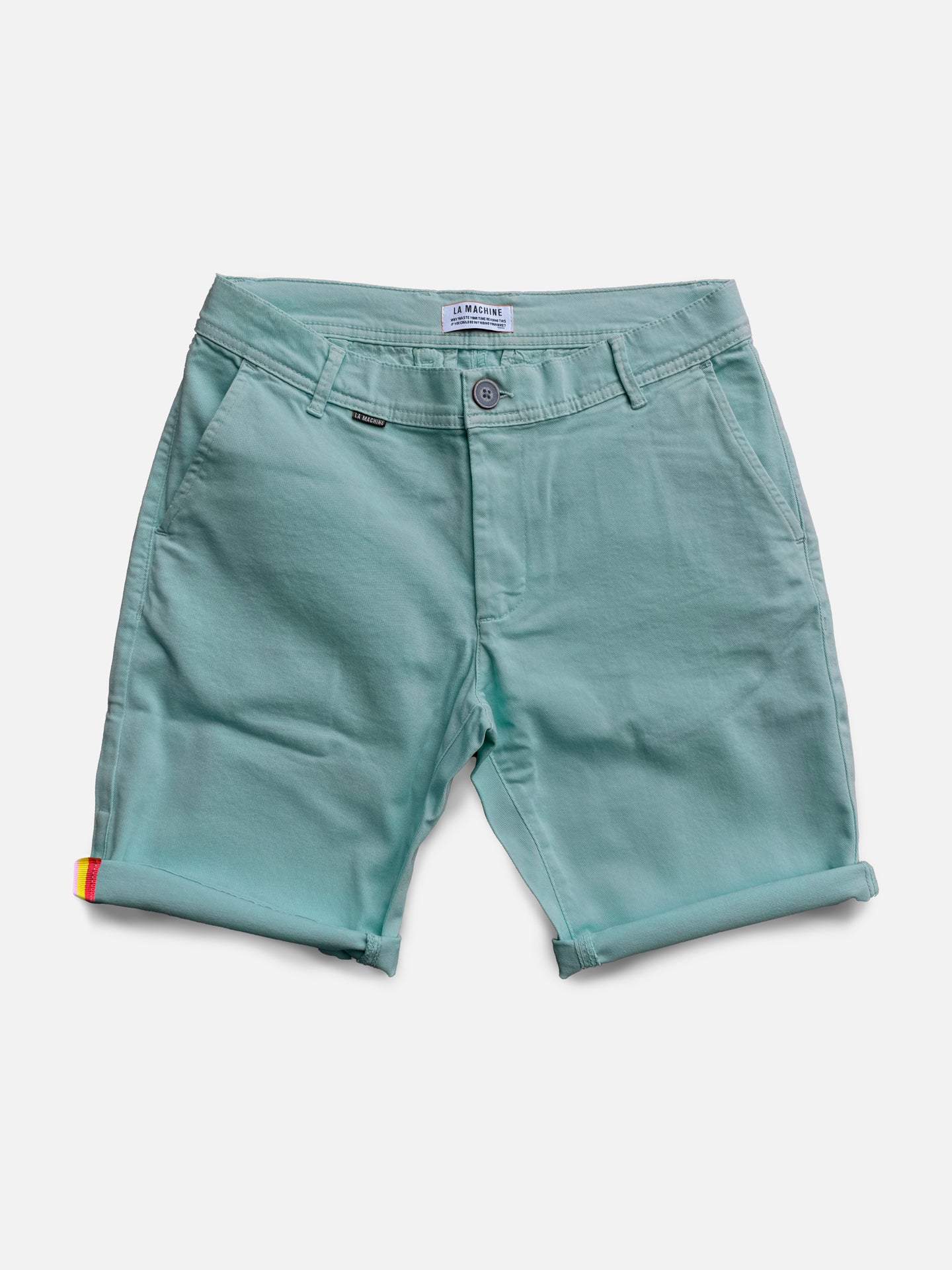 The Grand Tours - Rest Day Bermuda - Antarctics by La Machine Cycle Club are light teal men’s Bermuda shorts with a semi-tailored fit, rolled cuffs, front pockets, belt loops, button closure, and a rainbow accent on the left cuff.