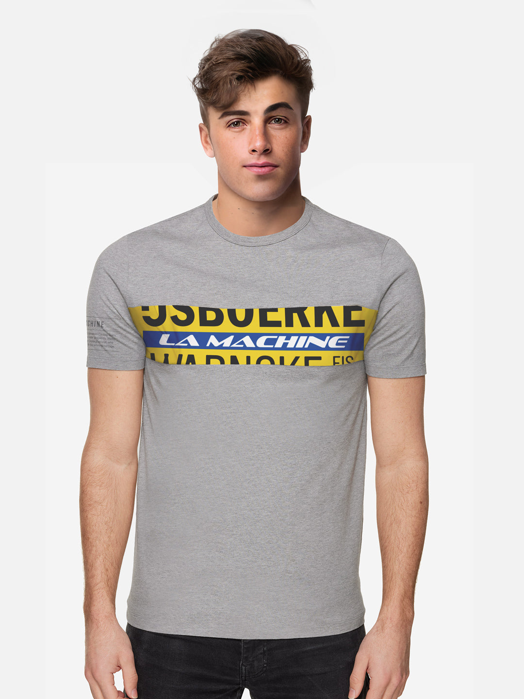 A young man with short brown hair models La Machine Cycle Club’s Ijsboerke - The Remix - T-shirt, a 100% cotton light grey unisex shirt with bold yellow, blue, and black graphic text, standing against a plain white background.
