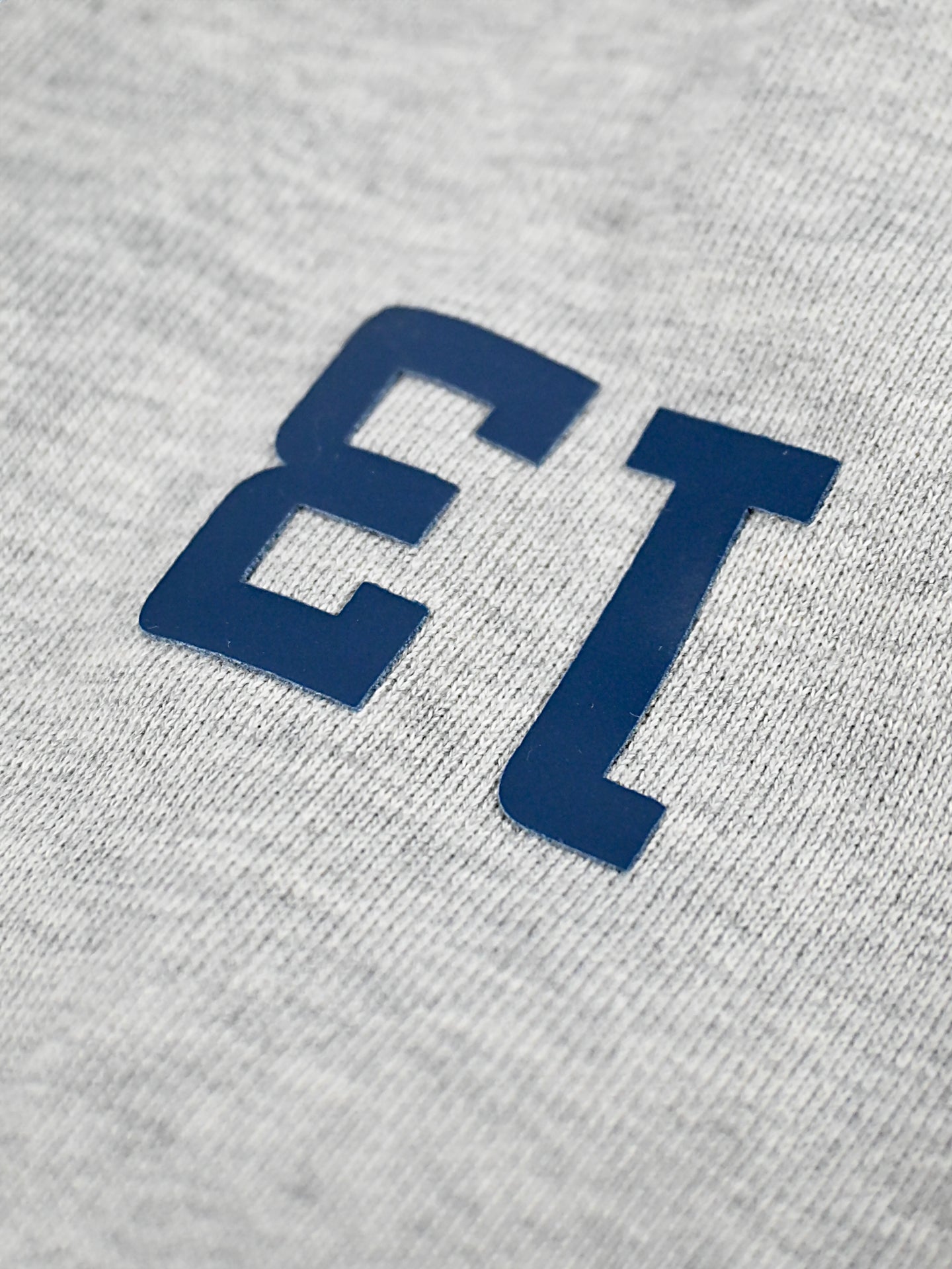 Close-up of the LMCC - University Hoodie by La Machine Cycle Club, featuring bold dark blue number 13 on gray unisex fabric. The background shows the sweatshirt’s texture, emphasizing its quality craftsmanship.