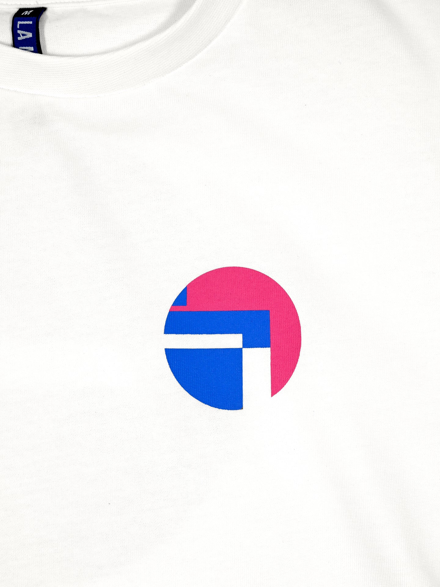 The Lampre Fondital 06 Loose Fit T-shirt by La Machine Cycle Club is a white tee with a chest circle graphic in pink and blue geometric shapes, divided by white lines, inspired by classic Lampre Fondital cycling jerseys.
