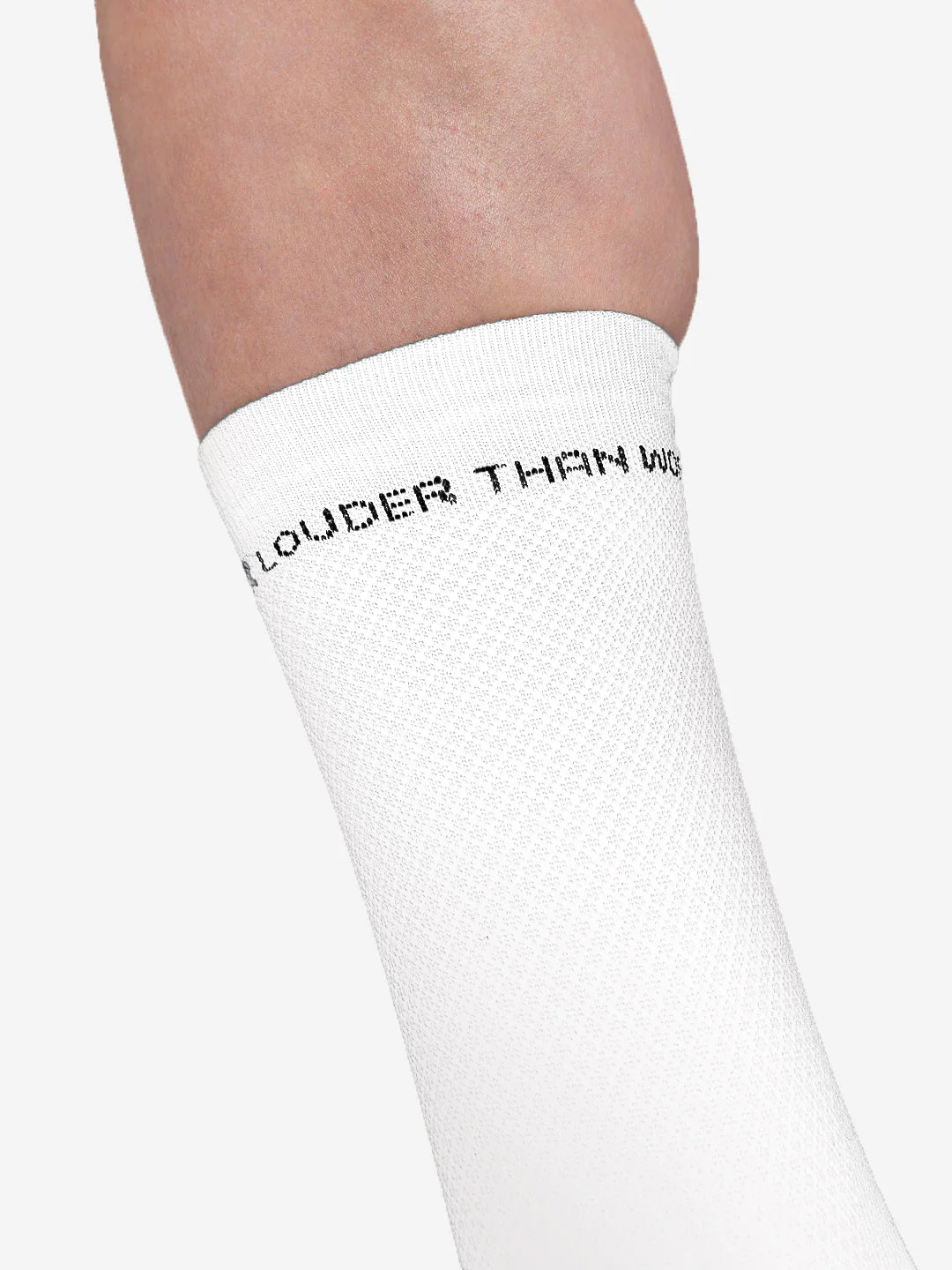 A close-up shows an ankle wearing a white La Machine Cycle Club “Louder than Words” cycling sock with black text near the top. The sock offers an elastic fit for comfort. Available in the Louder than Words - Cycling Socks Bundle.