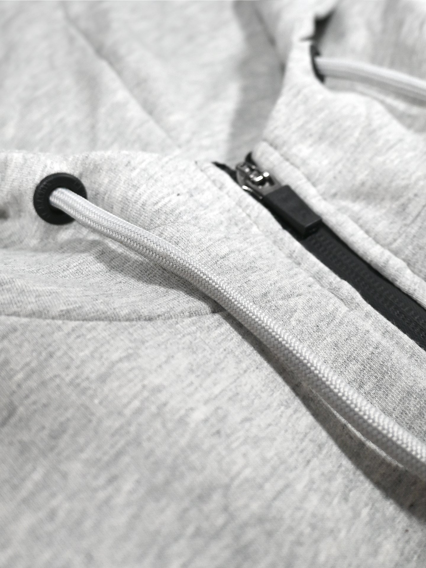 Close-up of the Lucky 13 - Zipped Hoodie by La Machine Cycle Club in Melange Grey, featuring a black zipper and white drawstrings threaded through black metal eyelets—the ultimate unisex hoodie for any style.