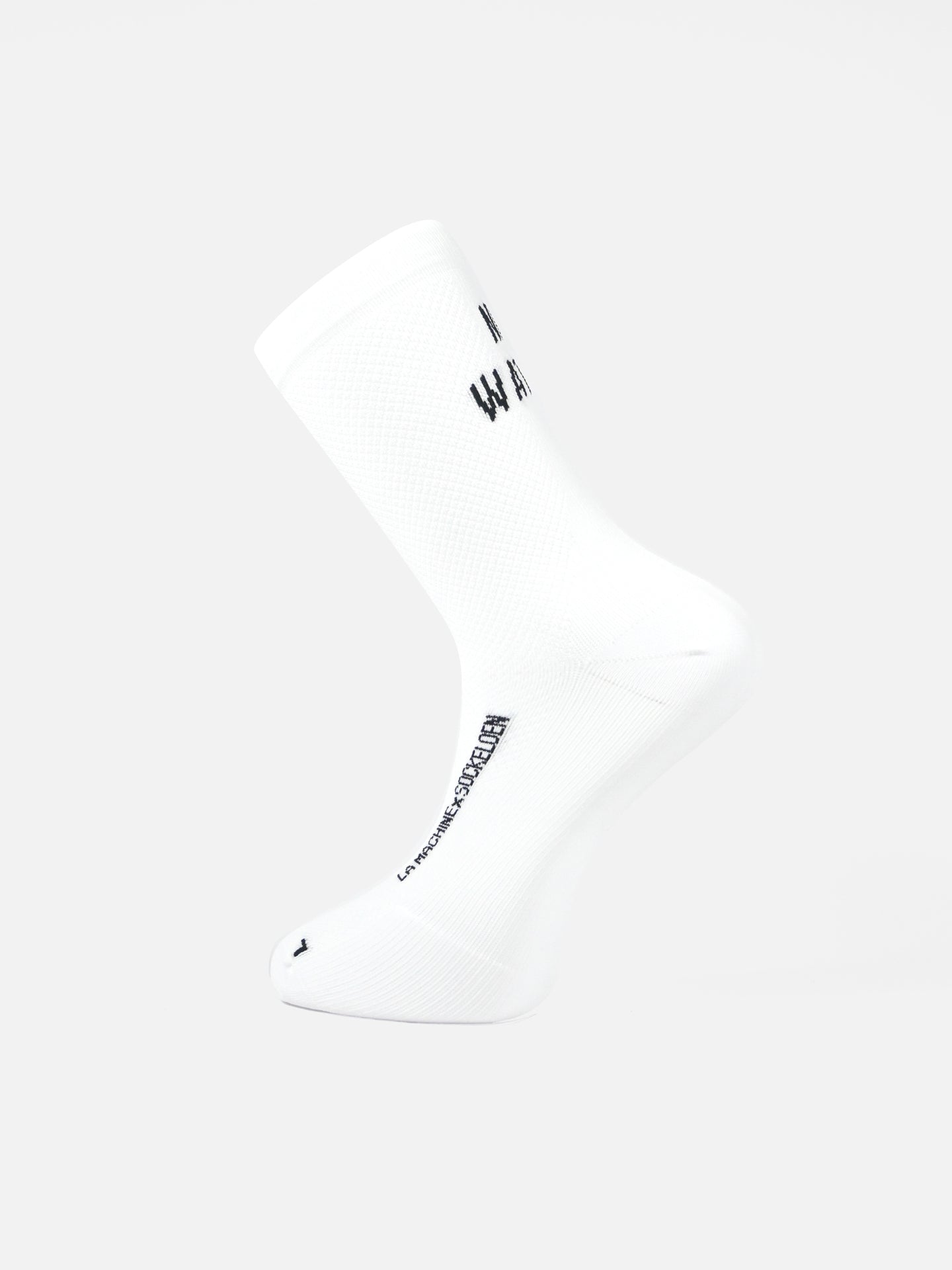 The La Machine Cycle Club’s No Watts No Glory white cycling sock, with black text on the side and bottom and a seamless toe, is displayed at an angle against a plain white background, with its toe pointing slightly upward.