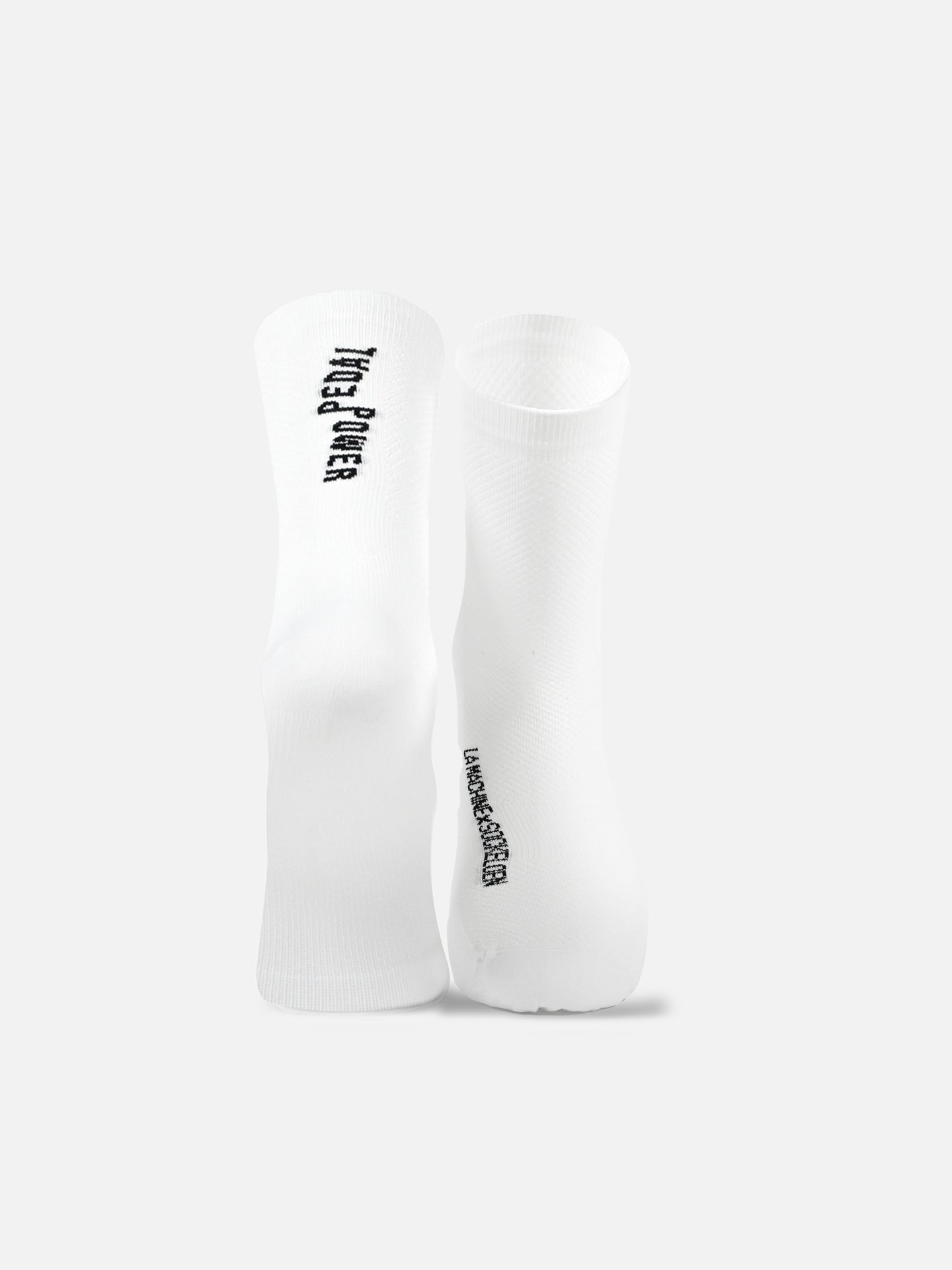 A pair of La Machine Cycle Clubs Pedal Power - Cycling Socks in white stands upright on a light gray background, each featuring black vertical text near the top and a seamless toe for comfort.