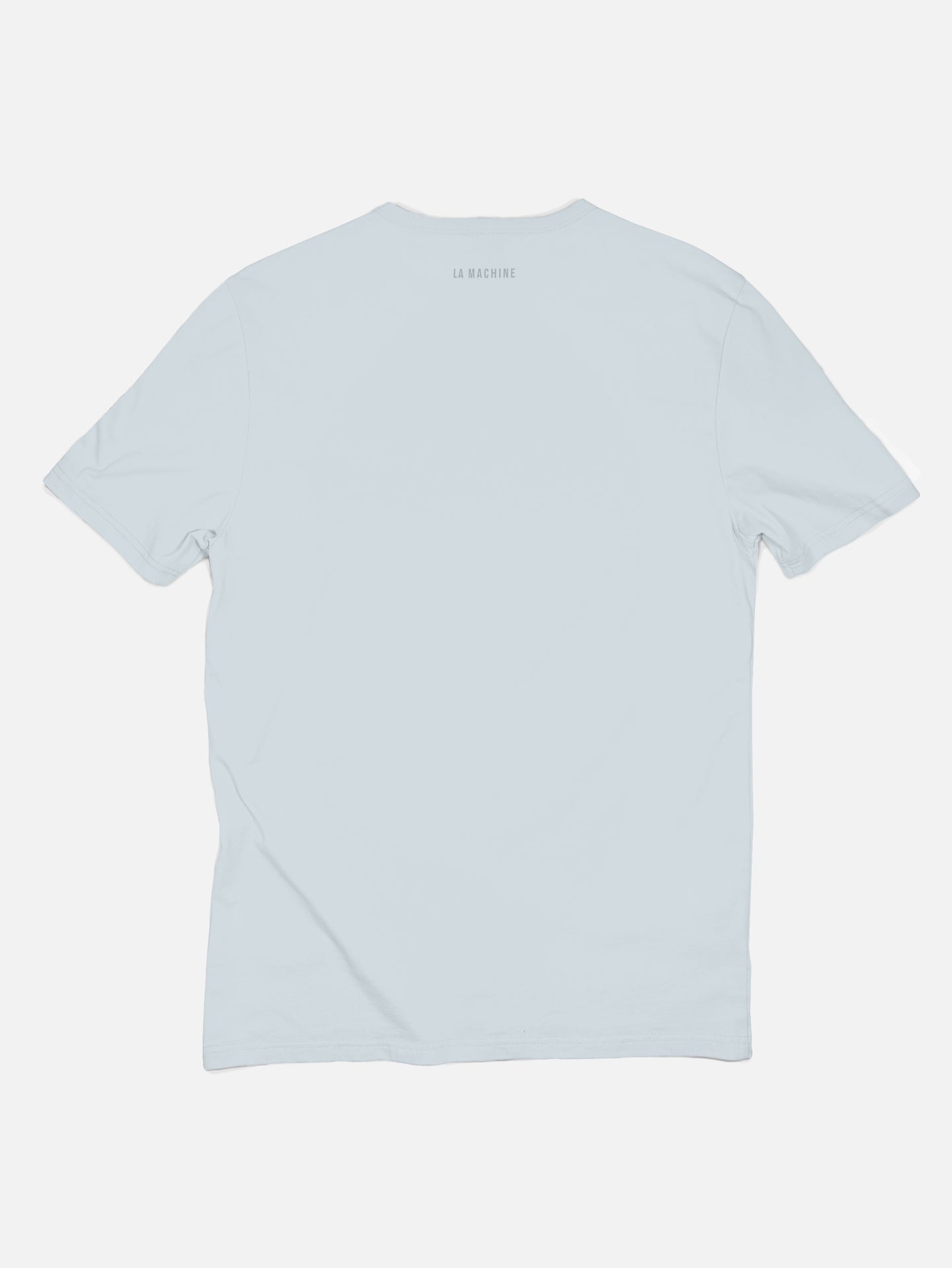 A plain light blue unisex Pedaleur de Charme - Embro T-shirt by La Machine Cycle Club, 100% cotton, shown from the back with small LA MACHINE text near the neckline.