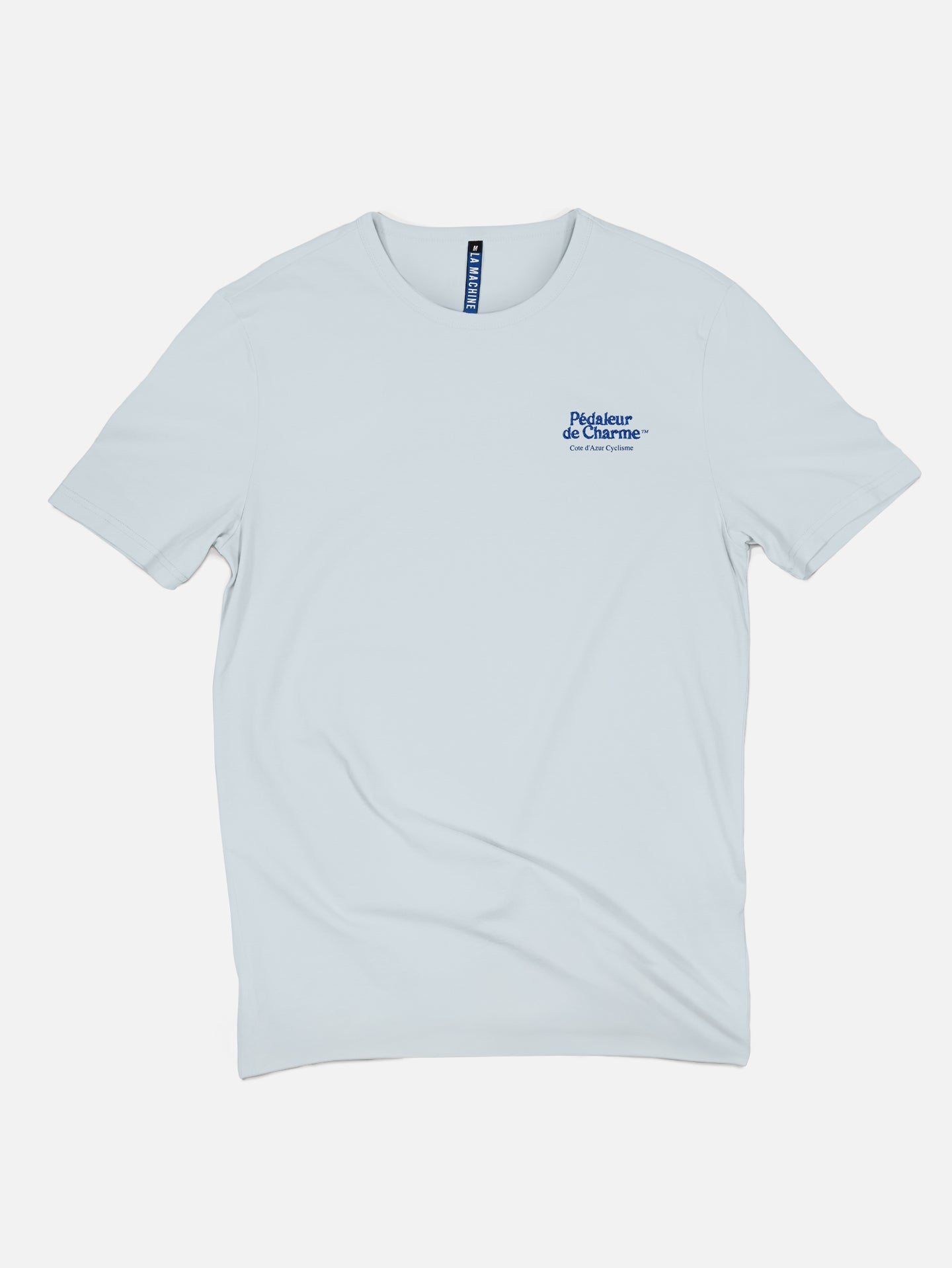 The La Machine Cycle Club Pedaleur de Charme - Embro T-shirt is a unisex, plain white 100% cotton tee with a crew neck, short sleeves, and a small blue French text logo embroidered on the upper left chest.