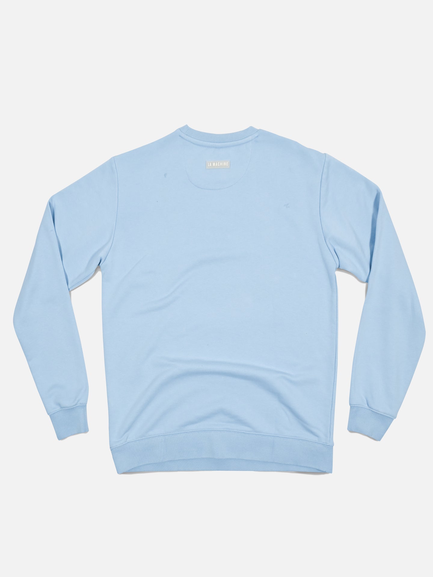 The Pedaleur de Charme sweatshirt in light blue by La Machine Cycle Club is laid flat, viewed from the back, with long sleeves, ribbed cuffs, and waistband—a tribute to Giro d’Italia legend Hugo Koblet.