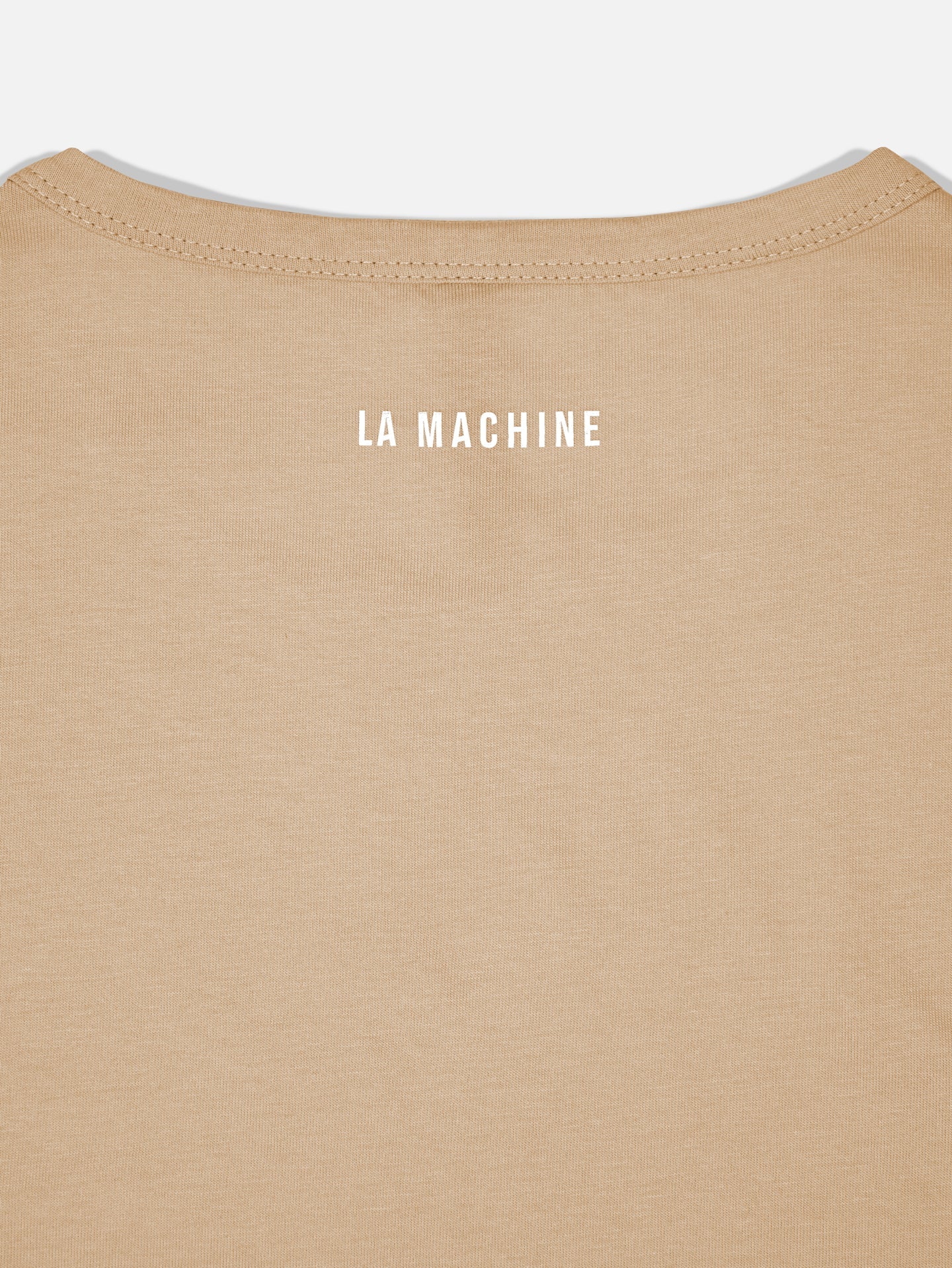 Close-up of the upper back of the La Machine Cycle Club Pedaleur de Charme - T-shirt - Sand, featuring LA MACHINE in white uppercase letters near the neckline—a subtle Giro d’Italia tribute.