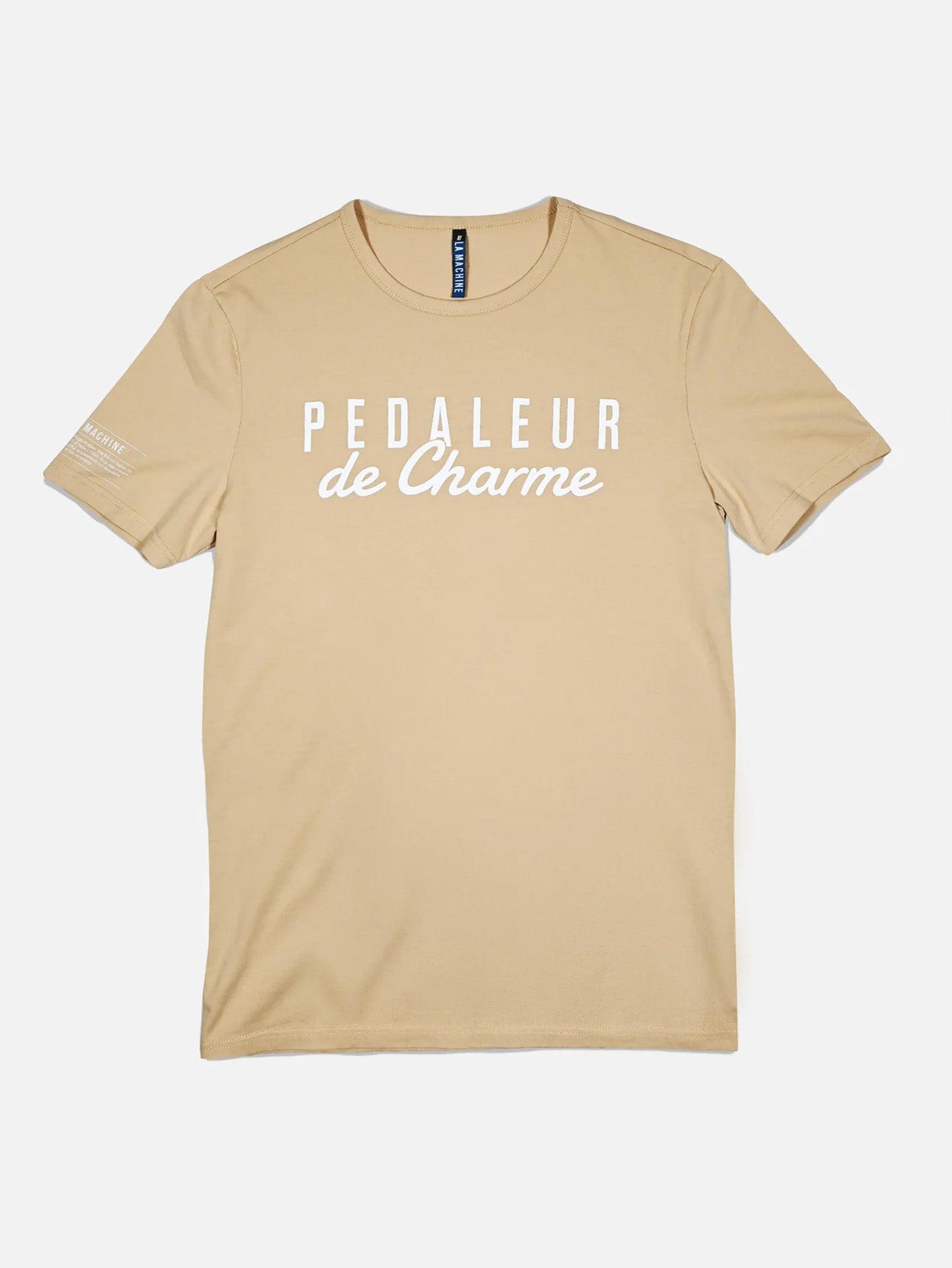 The La Machine Cycle Club Pedaleur de Charme T-shirt in sand is a unisex cotton tee featuring white PEDALEUR de Charme text on the front and small white text on the left sleeve, shown laid flat on a white background.