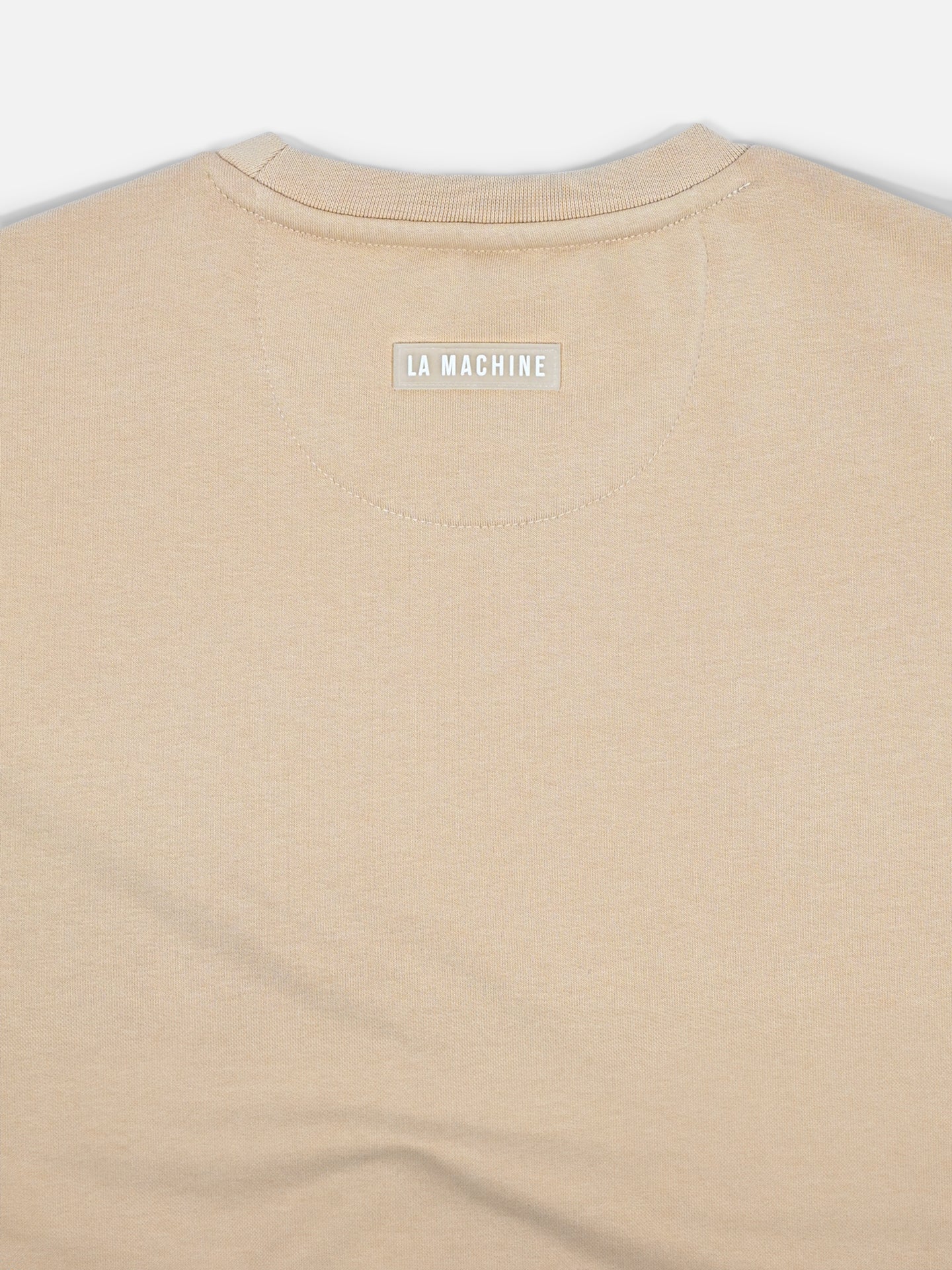 Close-up of the upper back of the Pedaleur de Charme - Sweatshirt - Sand by La Machine Cycle Club, featuring a small white LA MACHINE label near the neckline, inspired by classic Giro d’Italia apparel.