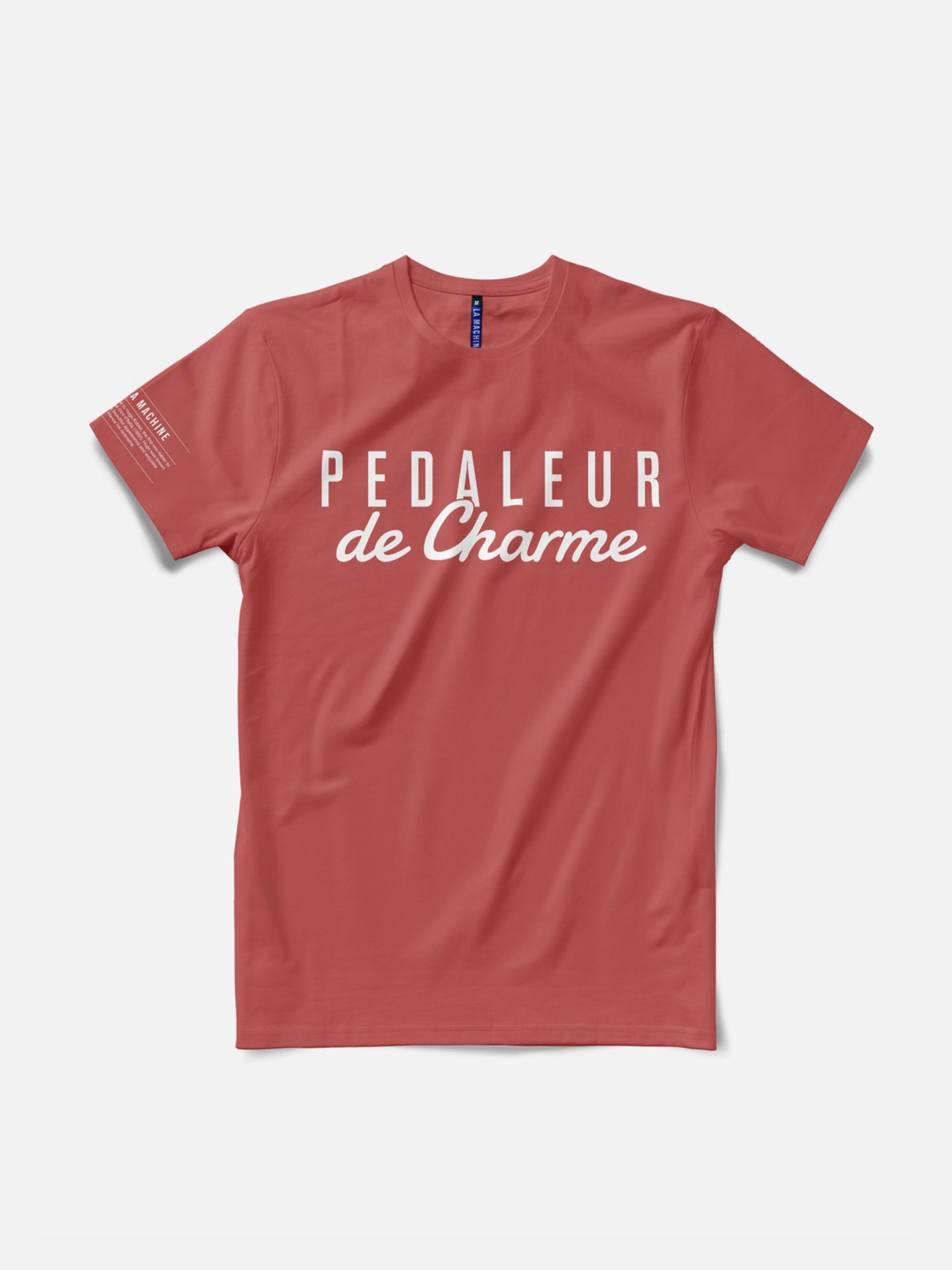 The La Machine Cycle Club Pedaleur de Charme T-shirt in coral features “PEDALEUR de Charme” in white, honoring Giro d’Italia winner Hugo Koblet. This premium cotton tee has short sleeves, a round neck, and a simple, casual style.