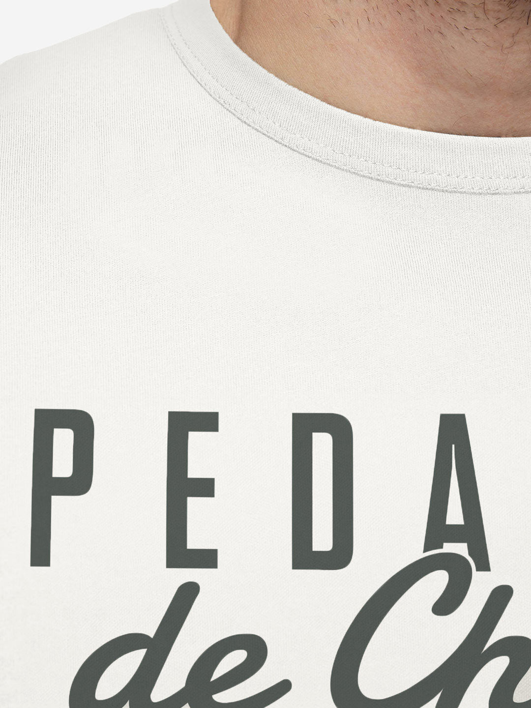 Close-up of a persons chest and neck wearing the La Machine Cycle Club Pedaleur de Charme unisex off-white T-shirt, featuring partial black text.