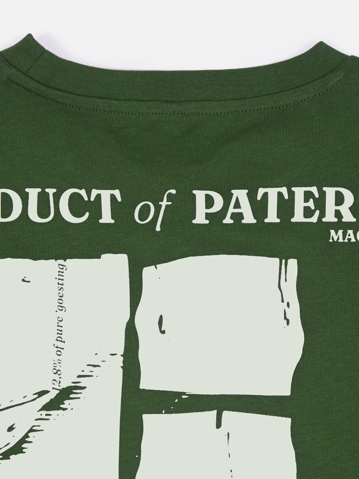 A close-up of the La Machine Cycle Club Product of Paterberg Loose Fit T-shirt shows heavy green cotton fabric with bold white block letters, abstract shapes, and small text—evoking the iconic Flanders climb.