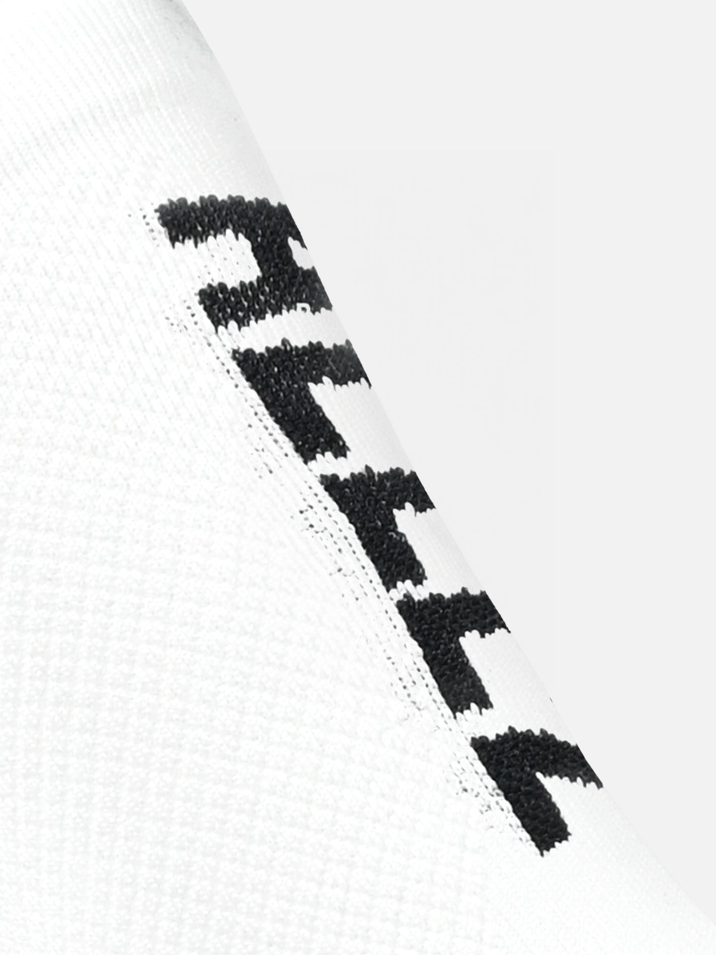 The Allez Allez Cycling Socks by La Machine Cycle Club feature an all-white textured fabric with a repeating black zigzag edge for optimal elastic fit.