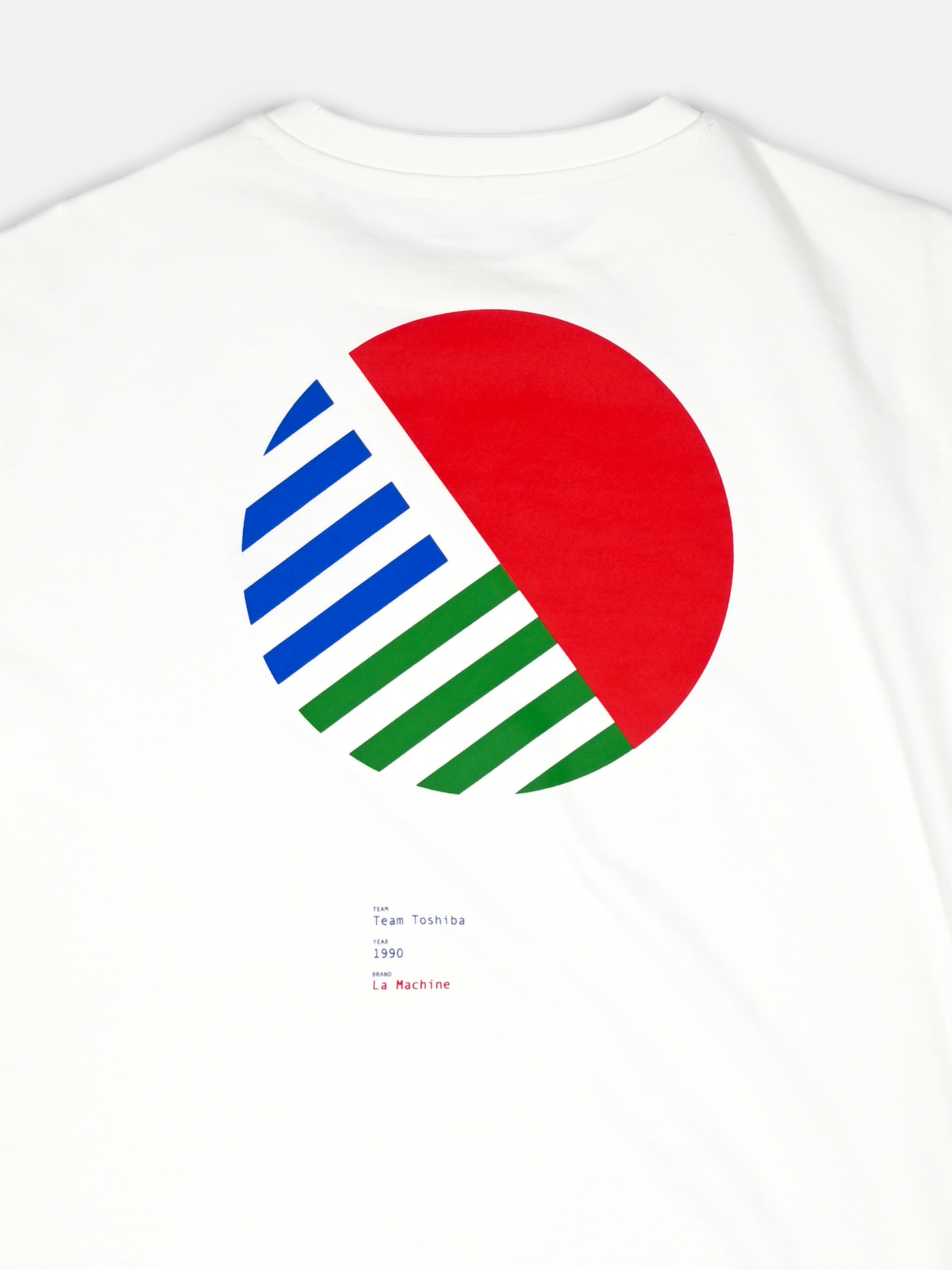 The La Machine Cycle Club Team Toshiba 90 Loose Fit T-shirt is white heavy cotton, with a large geometric back print: a diagonally split circle (upper right solid red; lower left blue and green striped). Small typed text sits underneath.