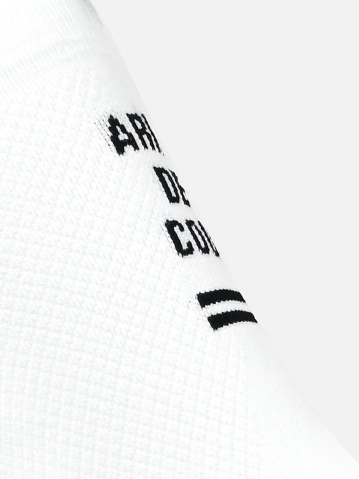 Close-up of La Machine Cycle Club’s Tête de la Course - Cycling Socks in white, showing black “TÊTE DE LA COURSE” text and two horizontal stripes. Features an optimum elastic fit for comfort. Set against a light grey background.