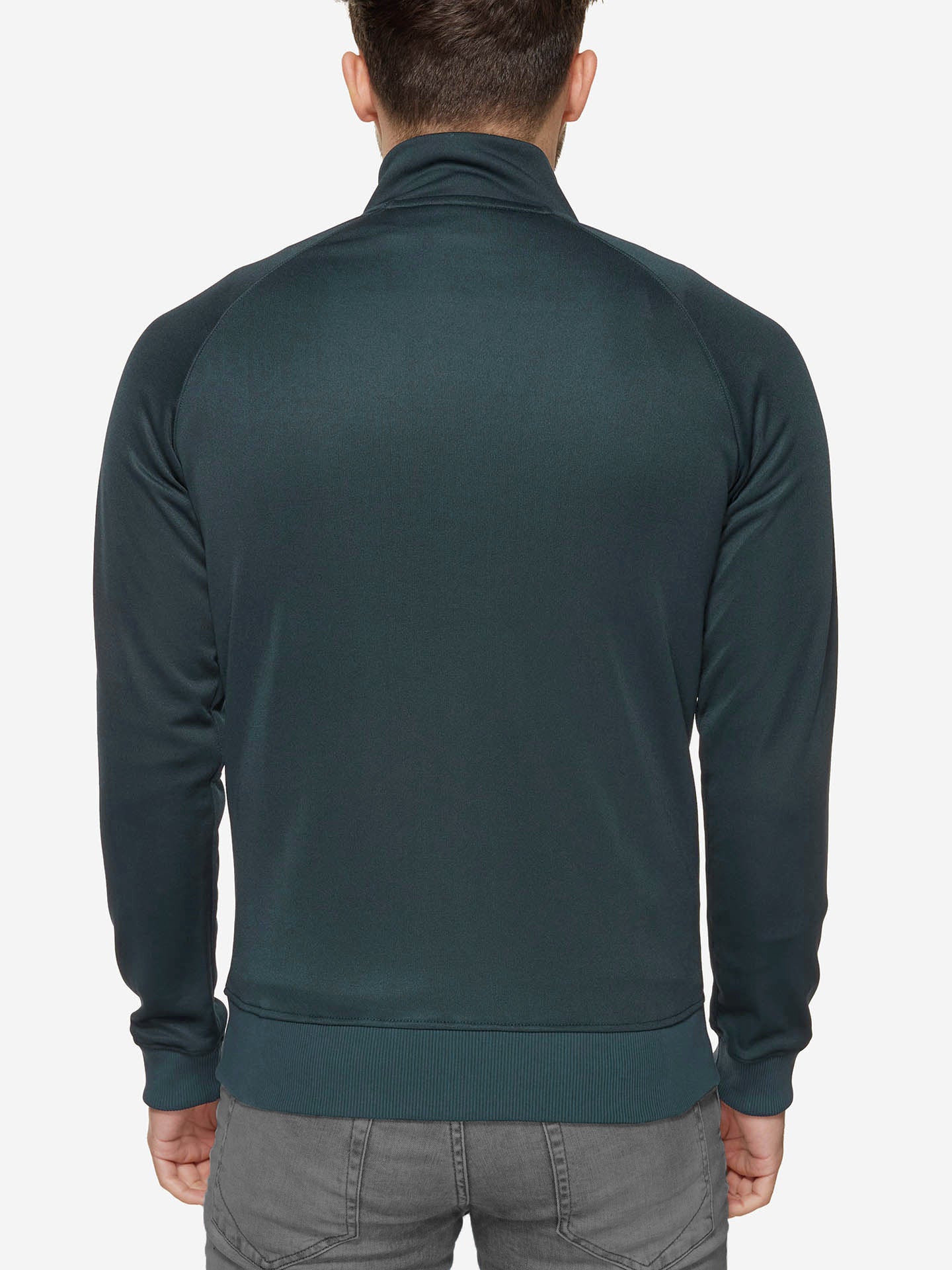 A man is seen from behind wearing the La Machine Cycle Club Food of Champions - Track Jacket in Atlantic Deep and gray pants, standing against a plain white background.