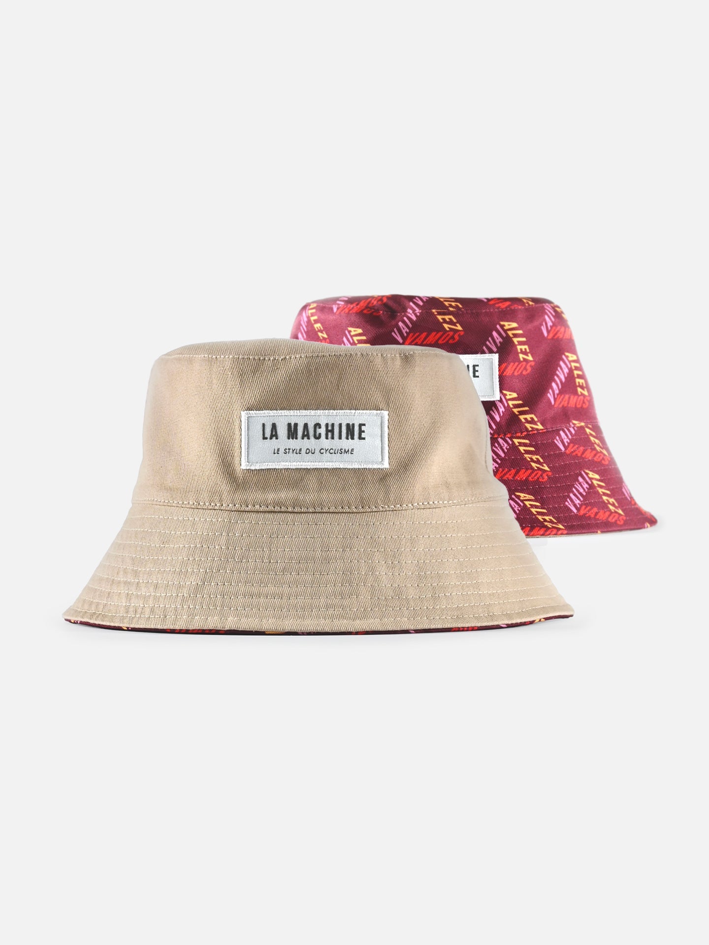 The La Machine - Reversible Bucket Hat by La Machine Cycle Club features a beige side with a white LA MACHINE patch and a red side with a yellow geometric pattern—ideal for Grand Tour fans who want versatile, cycling-inspired style.
