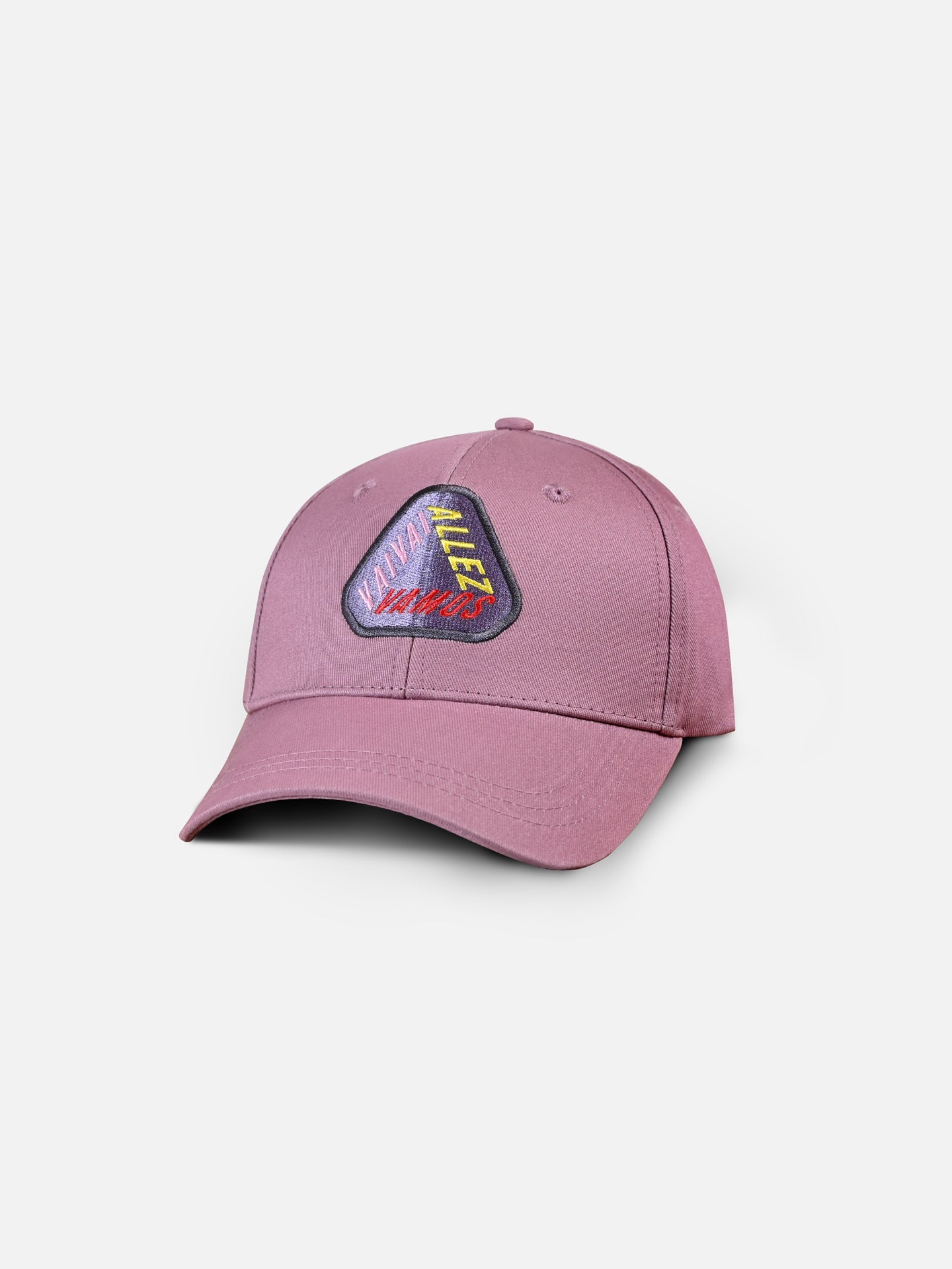 The Vai, Allez, Vamos - Casual Cap by La Machine Cycle Club is a mauve baseball cap with a curved brim and a vibrant geometric Tour de France-inspired embroidered patch, shown against a plain white background.