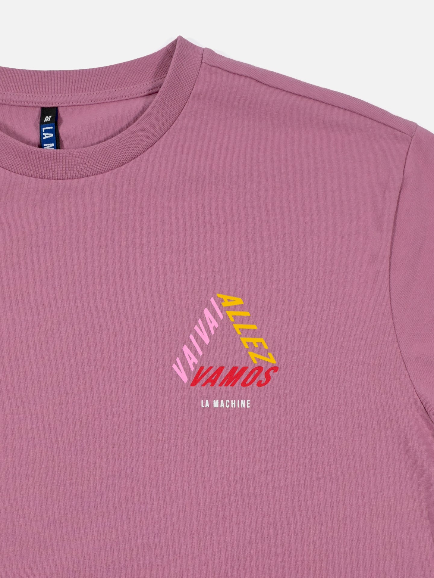The Vai Allez Vamos Loose Fit T-shirt by La Machine Cycle Club is a mauve heavy cotton unisex tee featuring a small geometric chest print with VAI VAI (pink), ALLEZ (yellow), VAMOS (red), and LA MACHINE (white)—perfect for cycling fans.