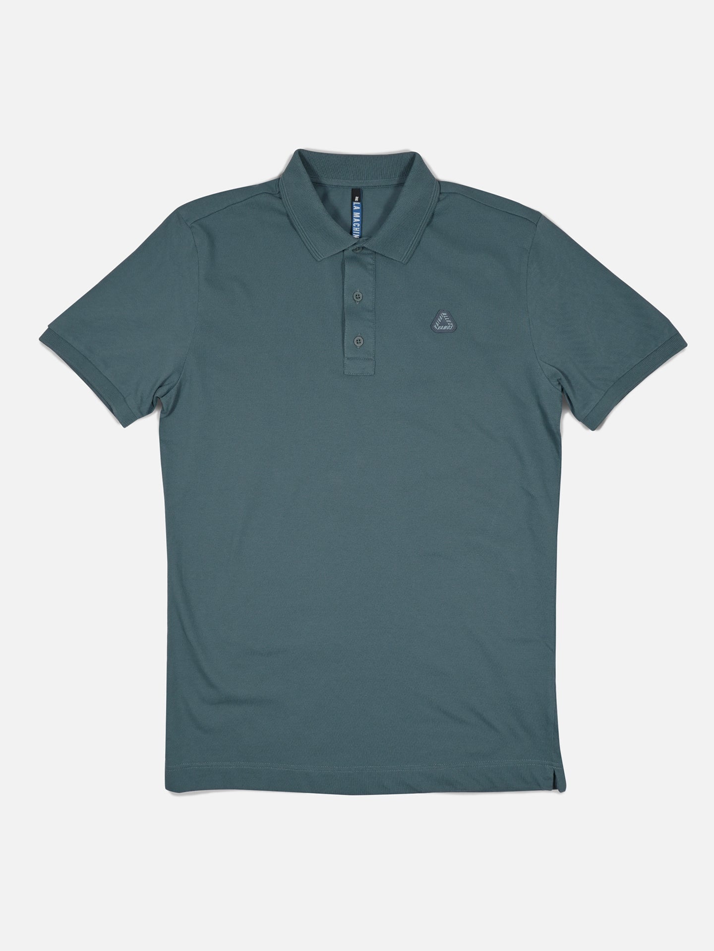 The Vai Allez Vamos Polo Shirt by La Machine Cycle Club in Orion Blue, featuring a collar, three buttons, and a small embroidered logo on the left chest, is laid flat on a white background.