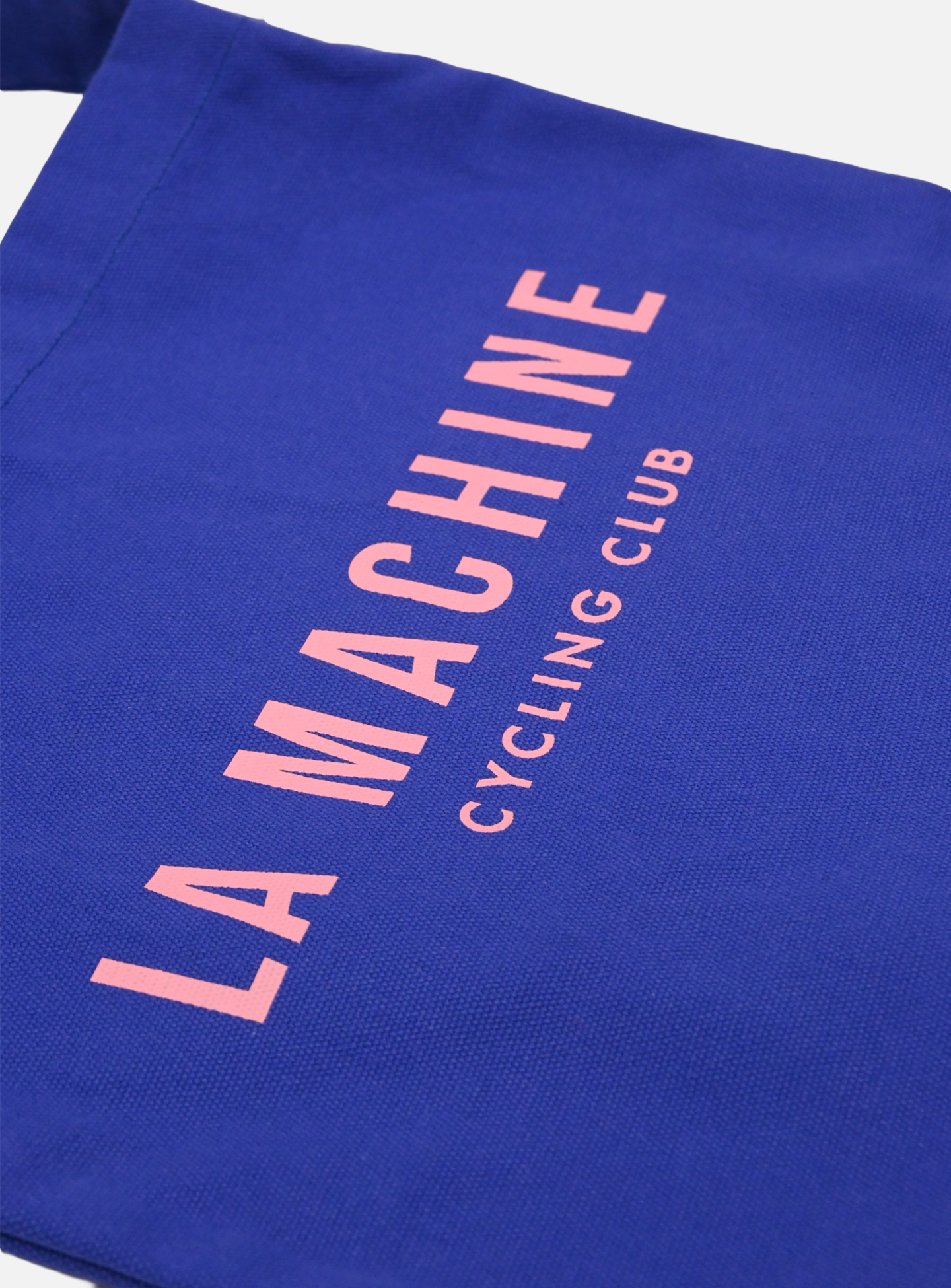 The La Machine Cycle Club Musette in blue features LA MACHINE CYCLING CLUB printed in pink caps—a stylish tote bag, perfect for everyday cycling.