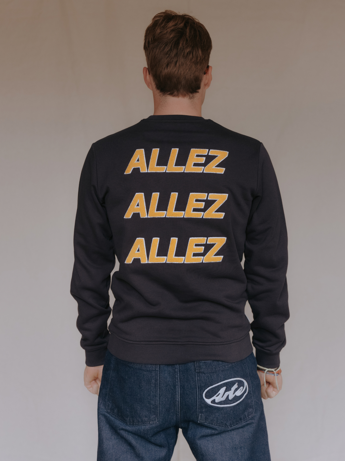 Close-up of the Allez Allez Allez print on the dark navy blue sweatshirt.