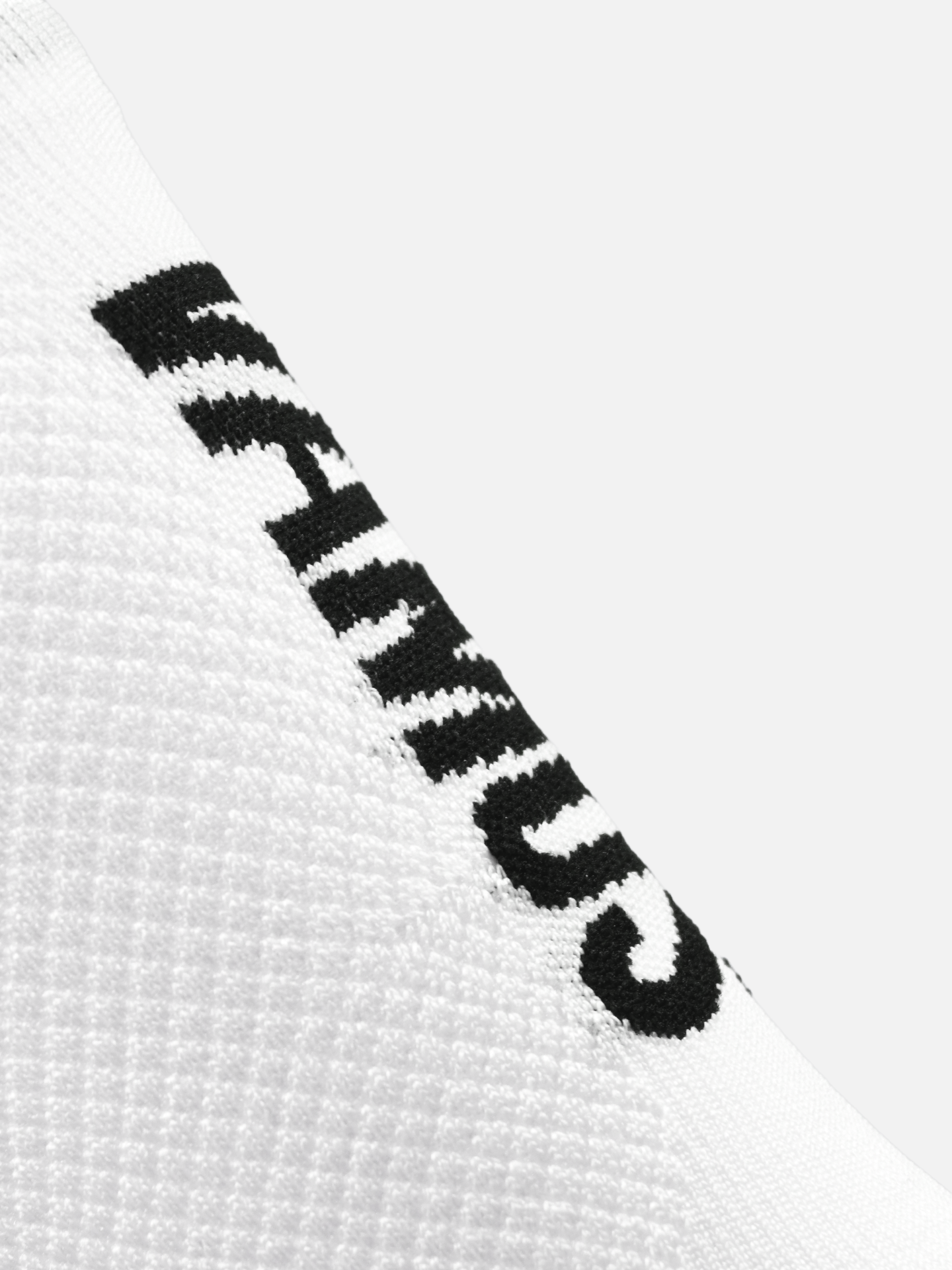 Close-up of La Machine Cycle Clubs Vamos - Cycling Socks in all white, shown diagonally on a plain white background. The sock features a partially visible black HUMAN print and textured fabric for optimal elastic fit.
