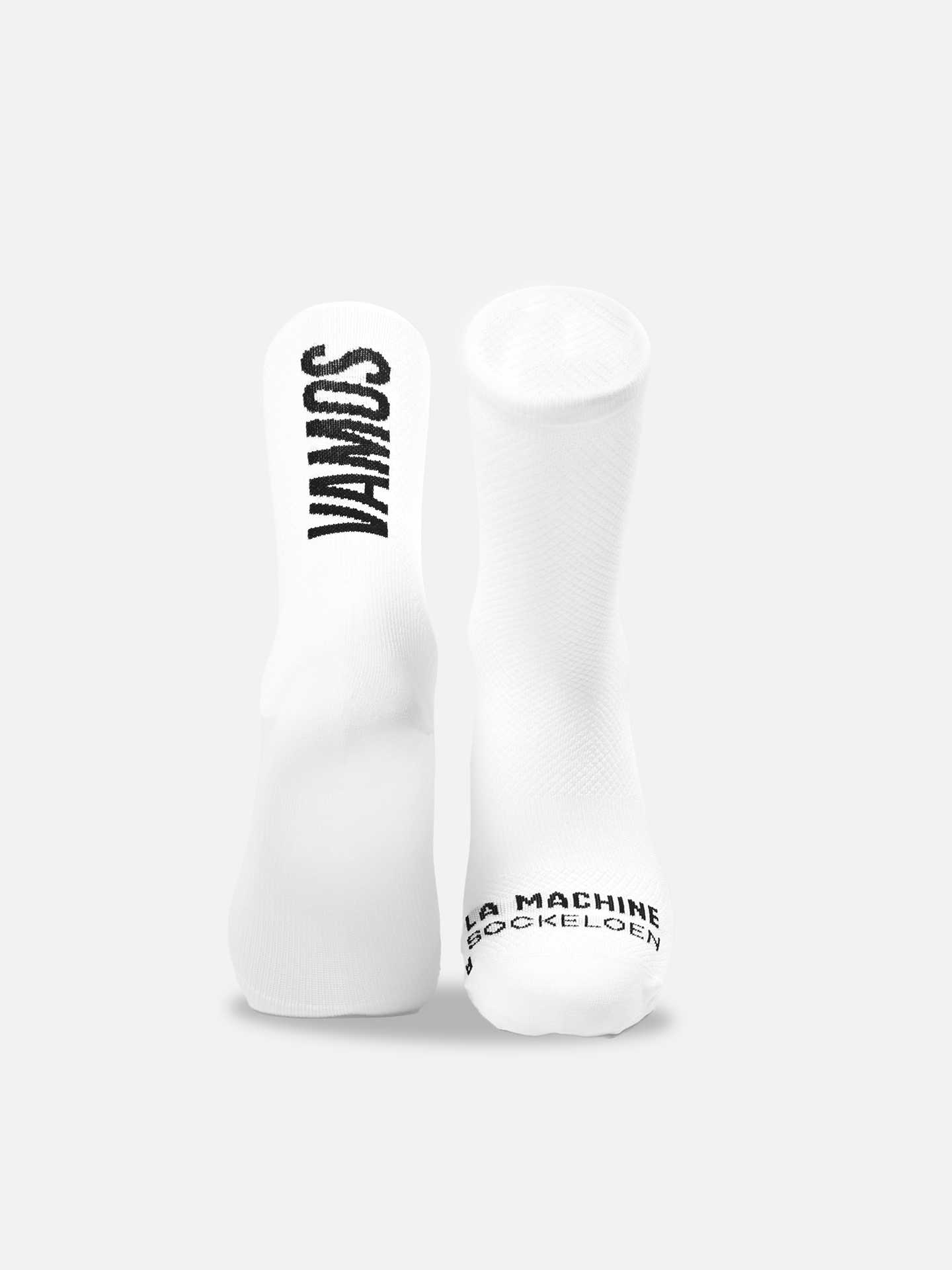 The Vamos Cycling Socks by La Machine Cycle Club, in all white, stand upright; VAMOS is printed vertically on the left sock, while LA MACHINE SOCKELOEN marks the right toe. Both feature a seamless toe for comfort on every ride.